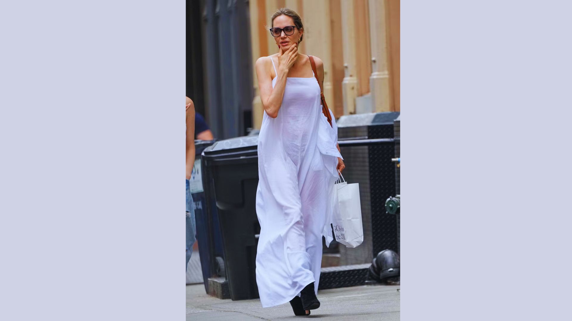 Angelina Jolie in a white dress walks on the street, reflecting a stylish casual outfit .