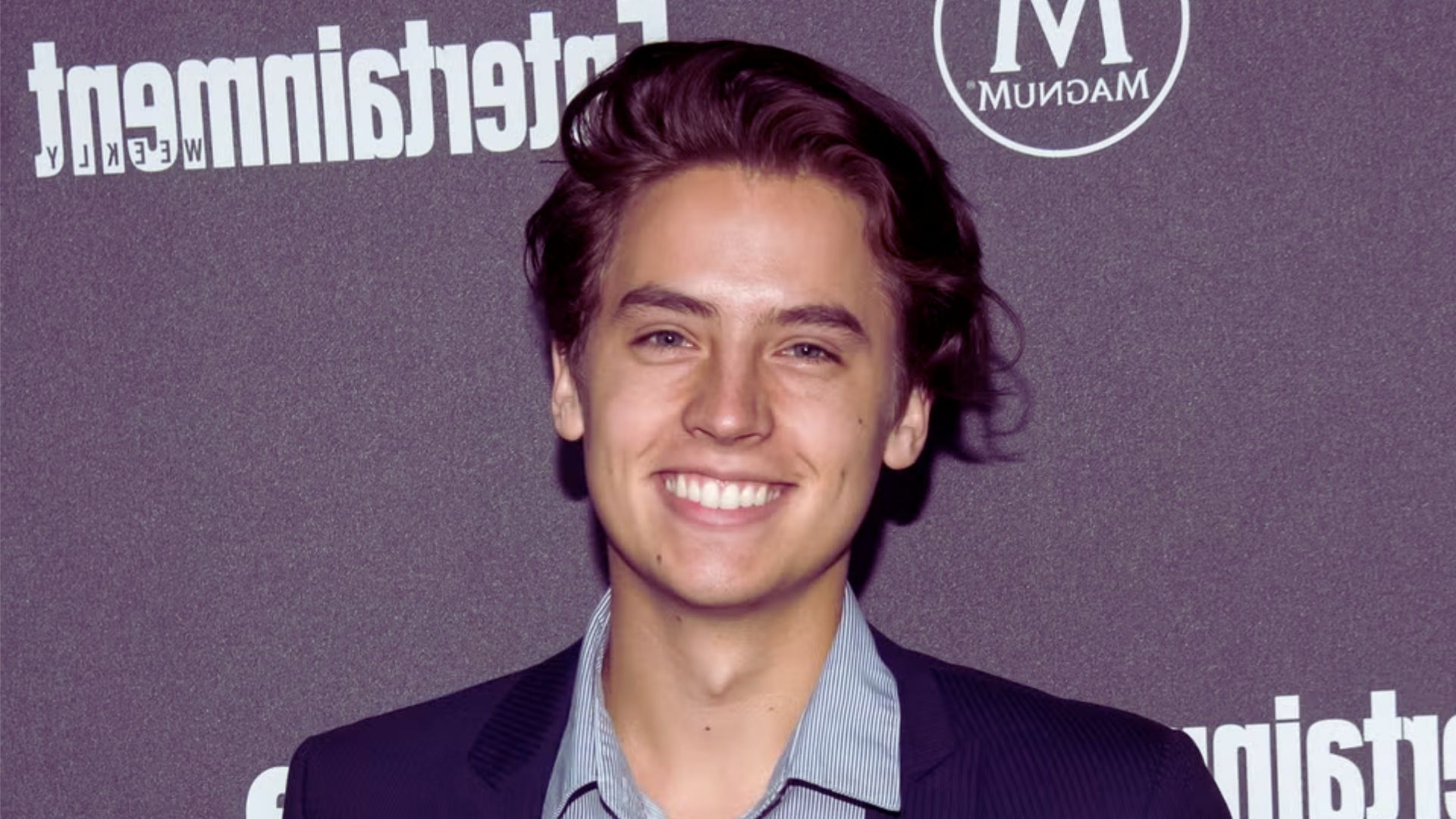 A young man with a bright smile looking directly at the camera.