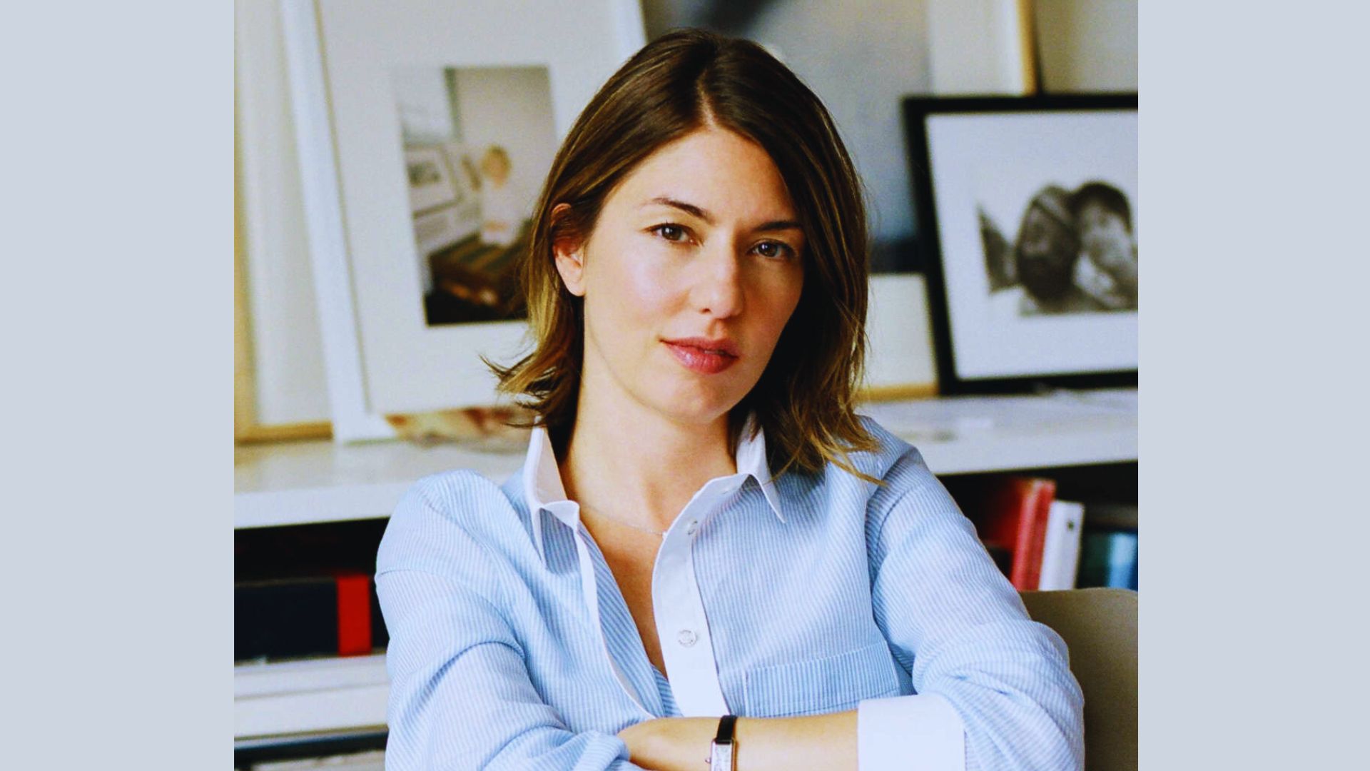 A woman wearing a blue shirt is seated at a desk, focused on her work.