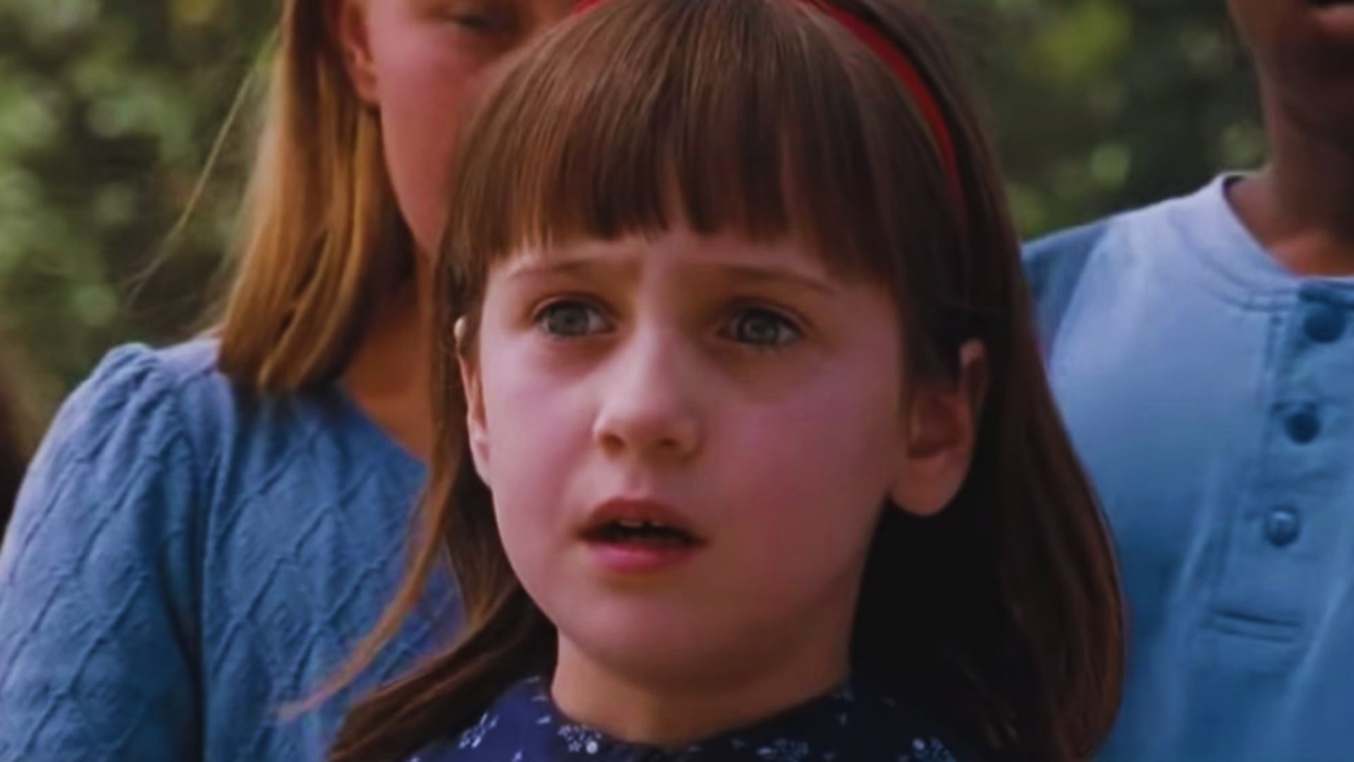 A young girl gazes thoughtfully into the distance, her expression curious and contemplative.