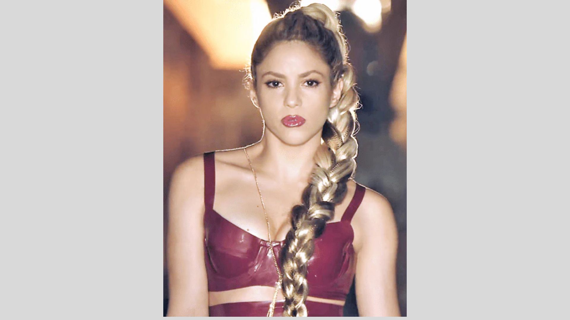 Shakira, with long braids, wears a vibrant red top, showcasing her signature style and charisma.