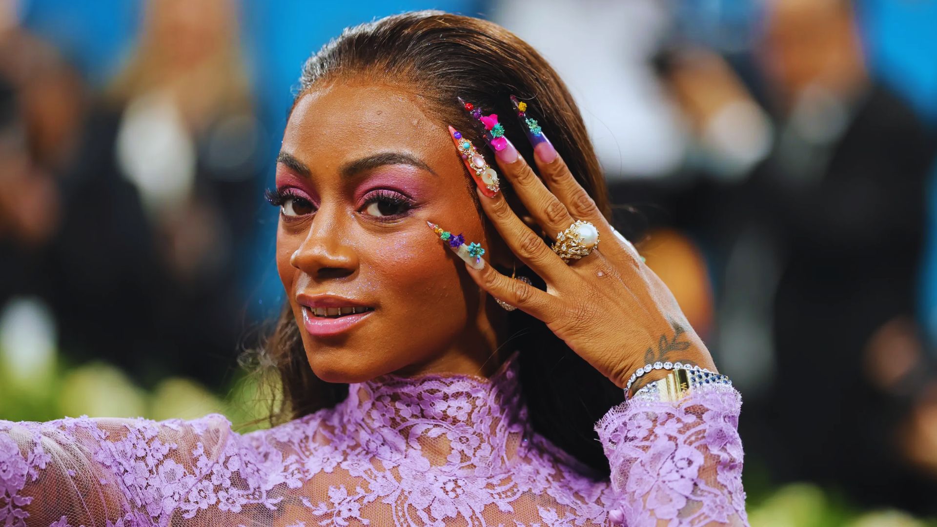 Sha'Carri Richardson at the Met Gala 2025, wearing a purple dress and purple nails, exuding elegance and fashion.
