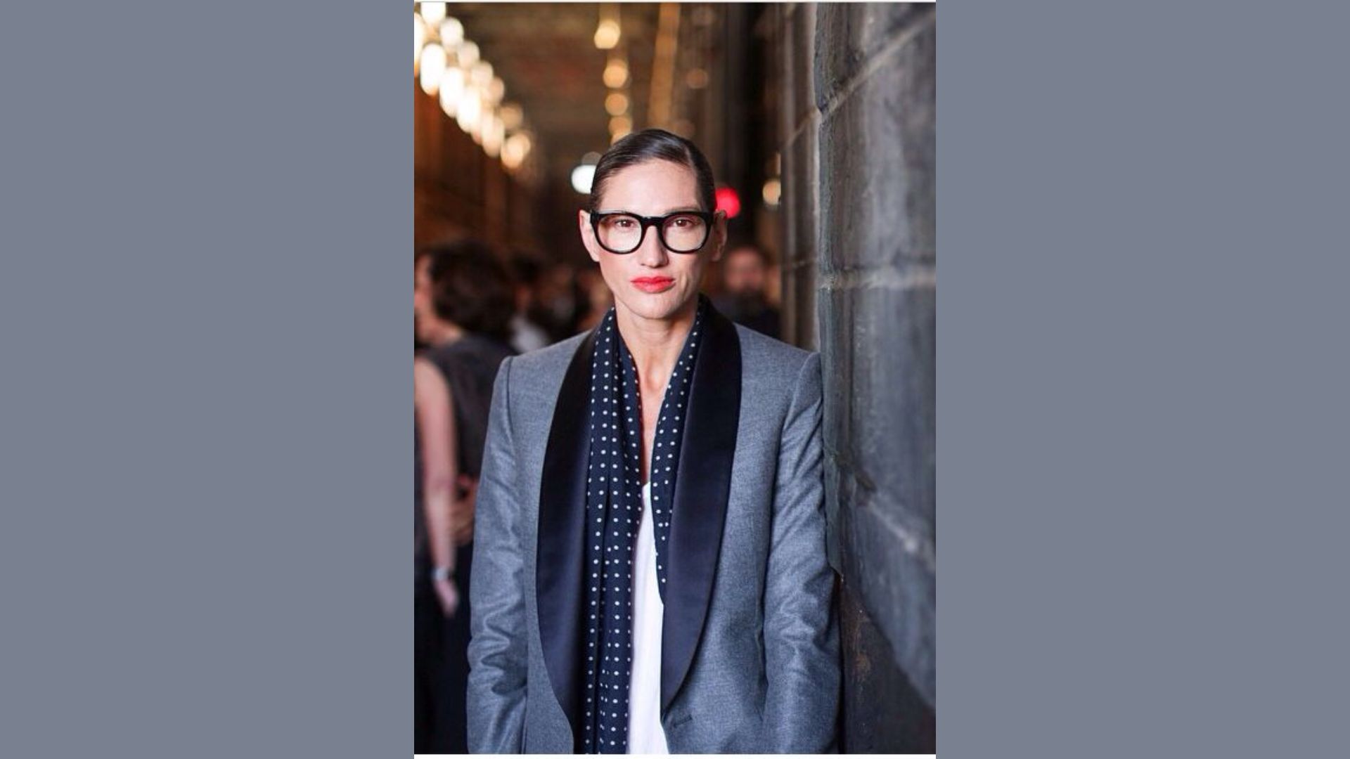 A woman in a suit and glasses, showcasing a polished and professional appearance.