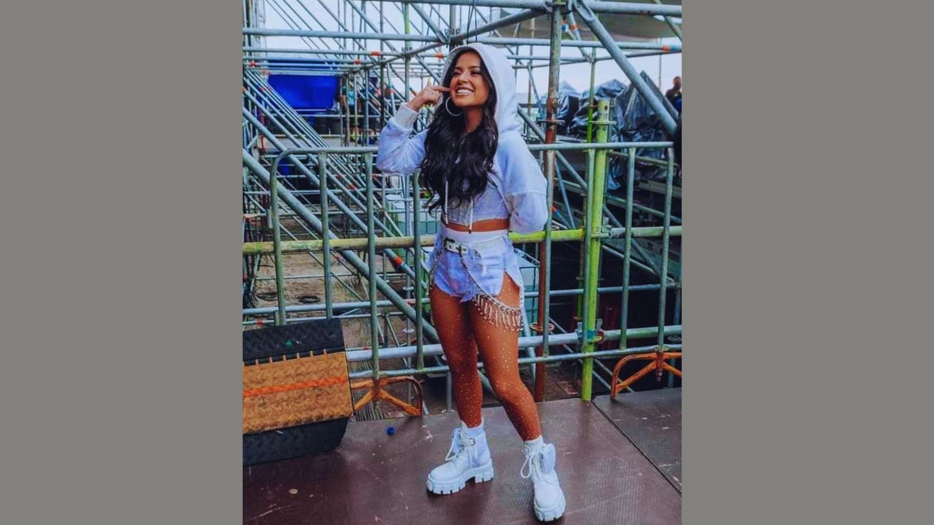 Person in a white crop top and blue shorts, standing casually outdoors.
