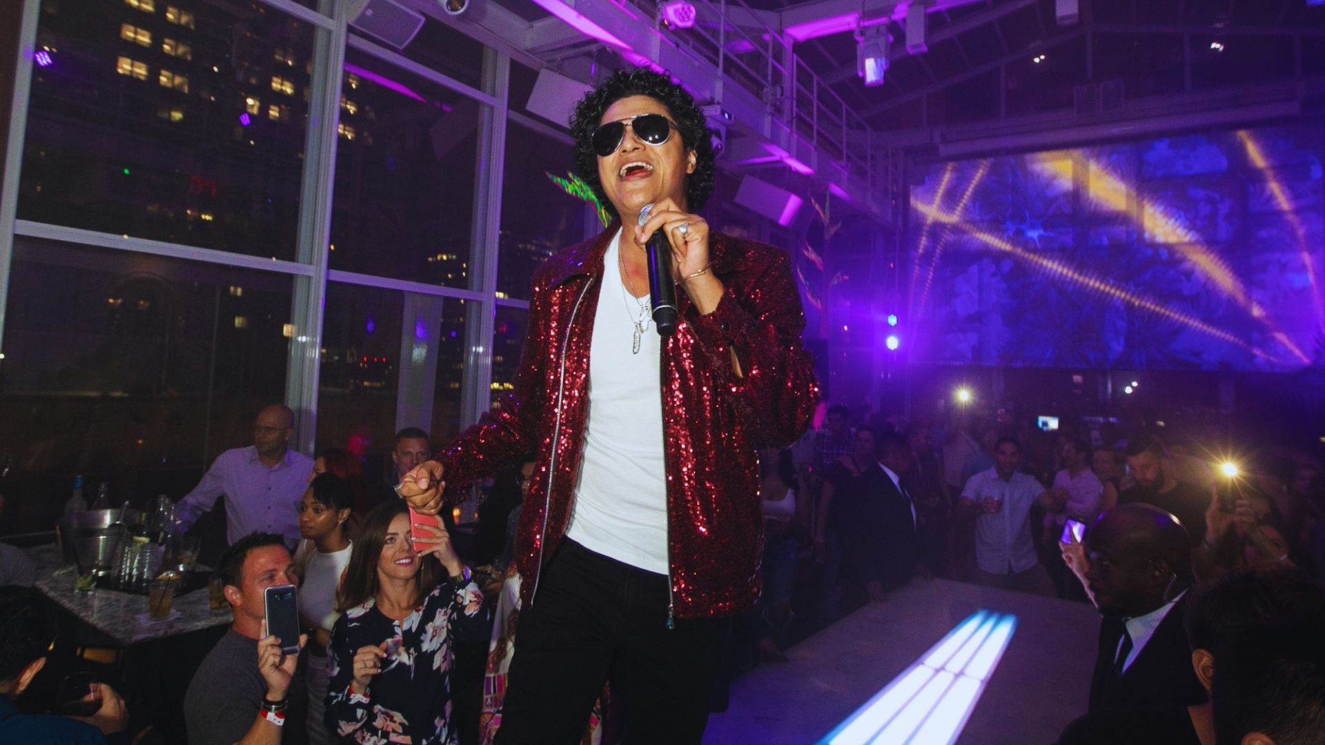 Bruno Mars in red shimmery jacket and black trouser.