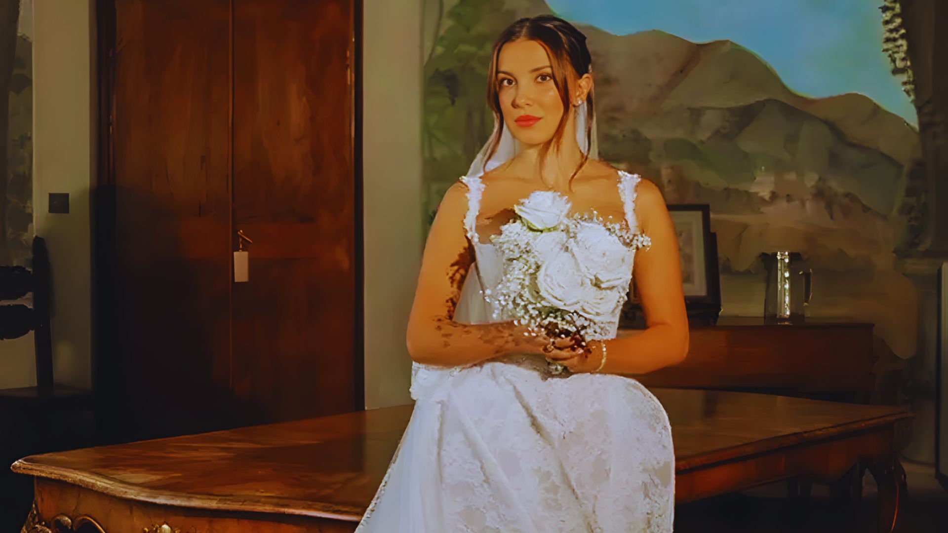 A bride in a wedding dress poses in front of an elegantly set table, showcasing her joyful moment.
