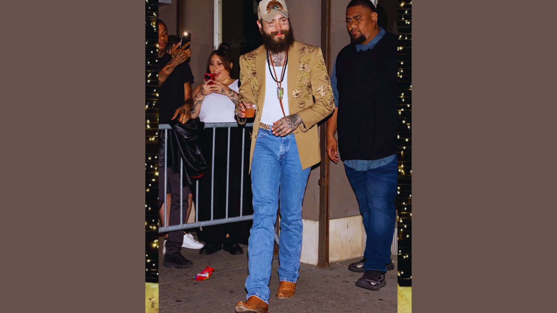 A bearded man wearing a hat walks down the street, surrounded by urban scenery.