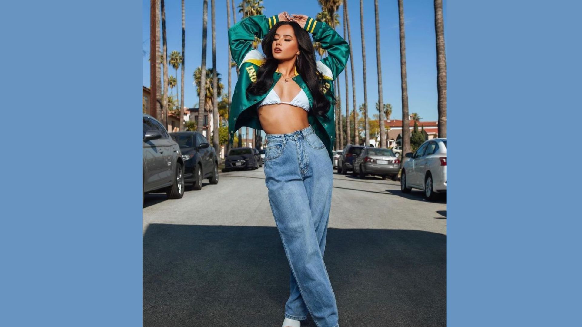 A woman in a crop top and jeans stands confidently in the middle of a street, surrounded by urban scenery.
