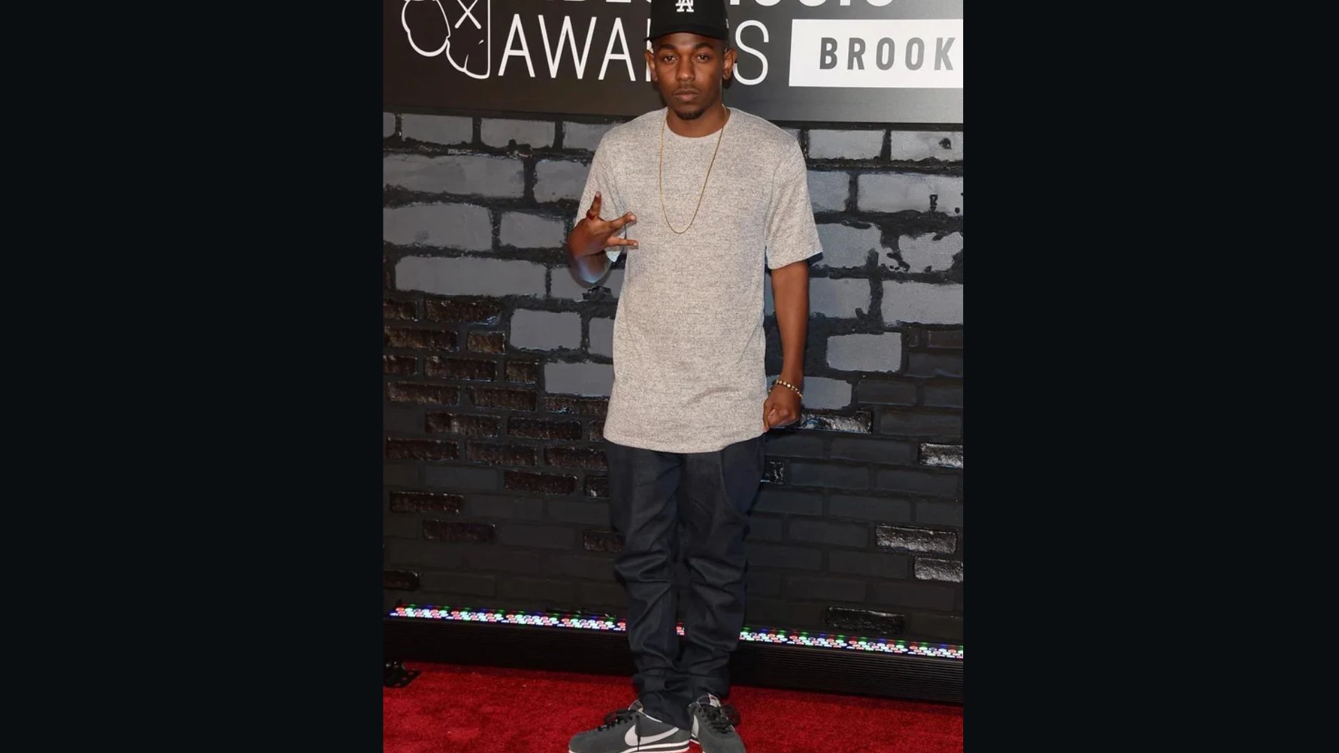Kendrick Lamar poses confidently on the red carpet, showcasing his signature style and composed presence.