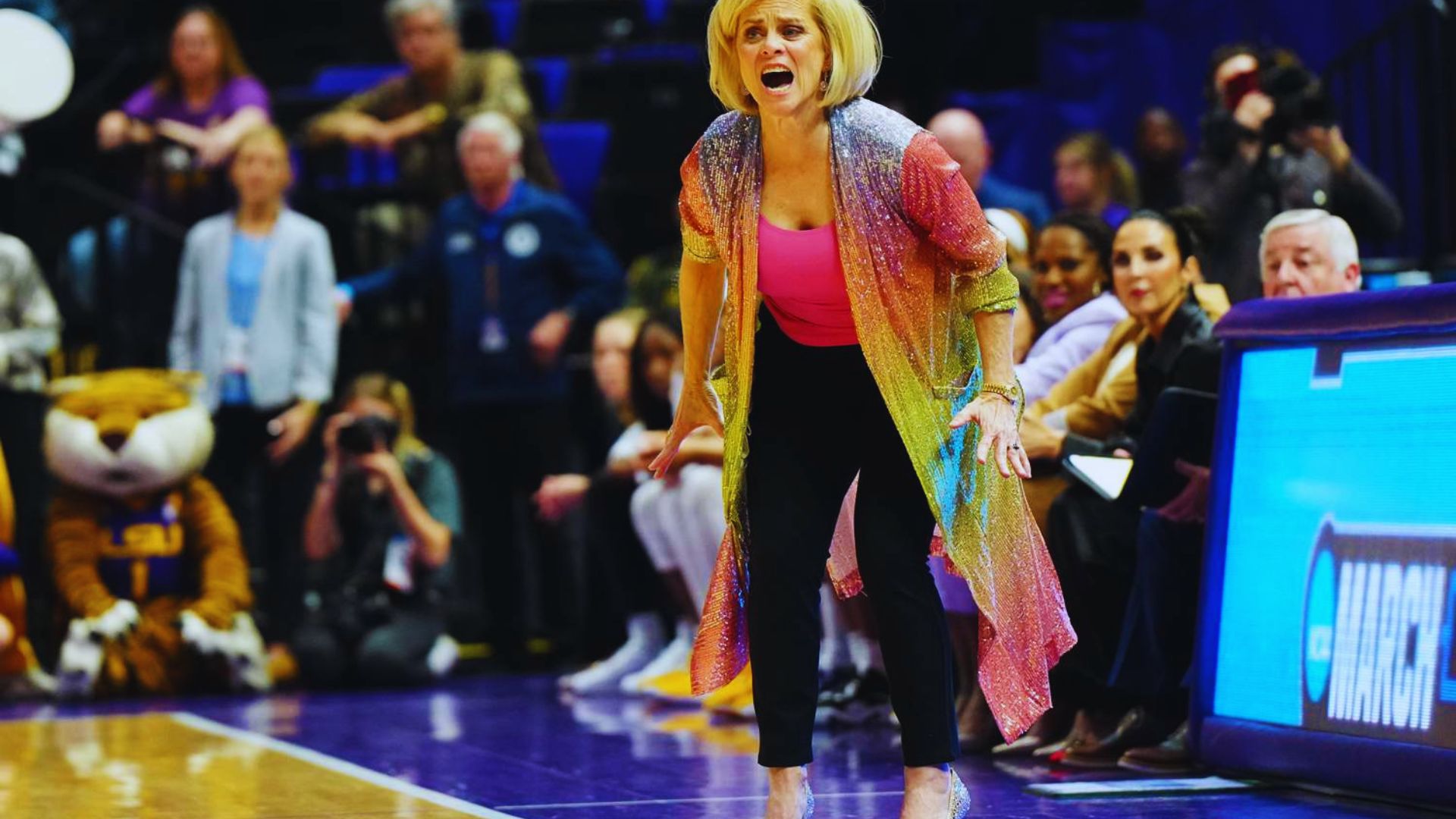 A woman wearing a pink shirt and black pants stands on the court, ready to play.