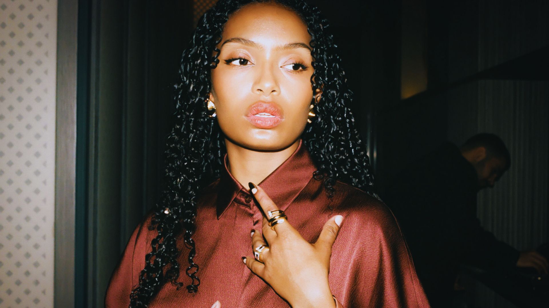 A woman with long hair wearing a ring on her finger, smiling softly at the camera.