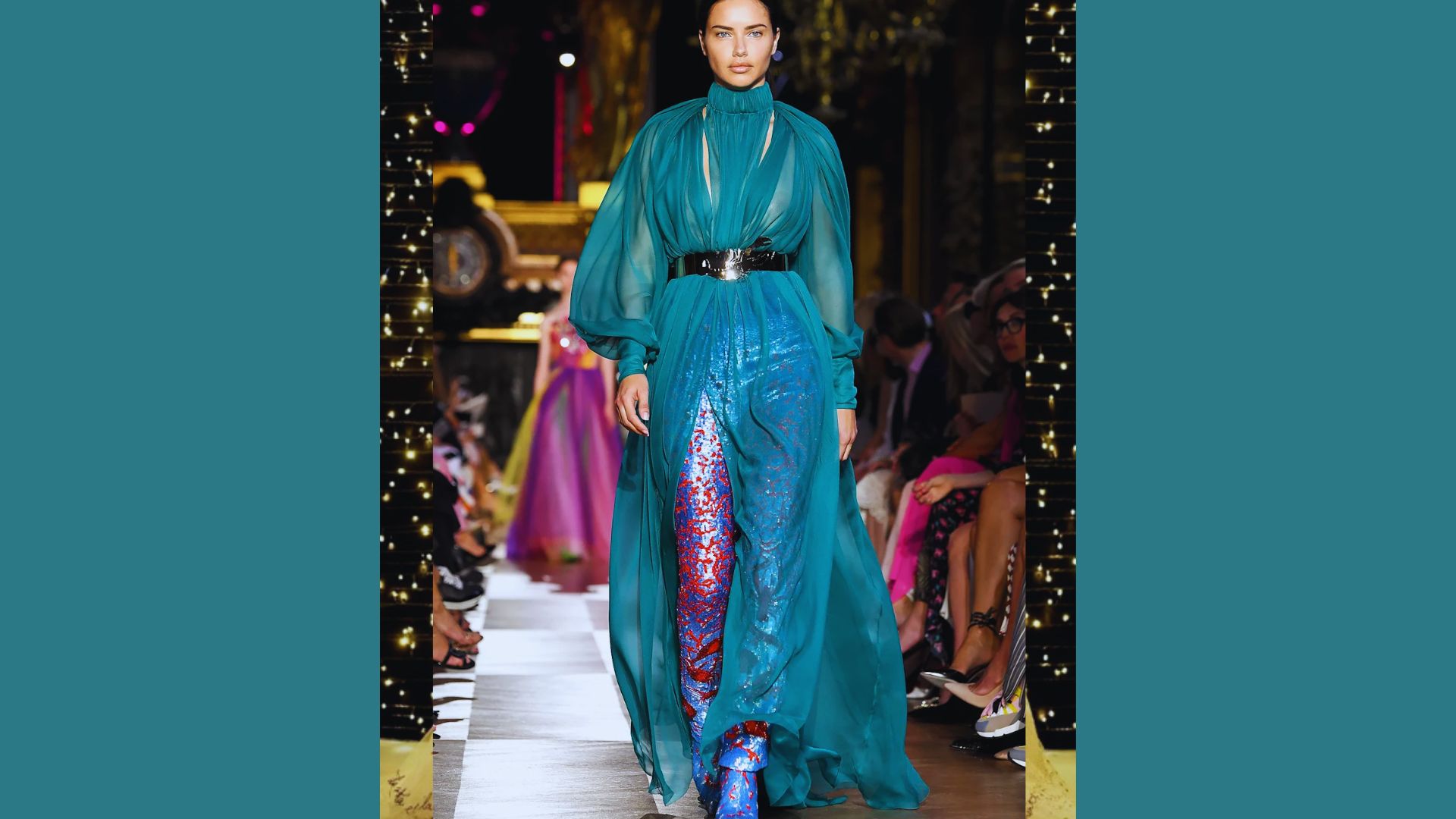 A model confidently walks the runway in a flowing blue dress, showcasing the latest fashion design.
