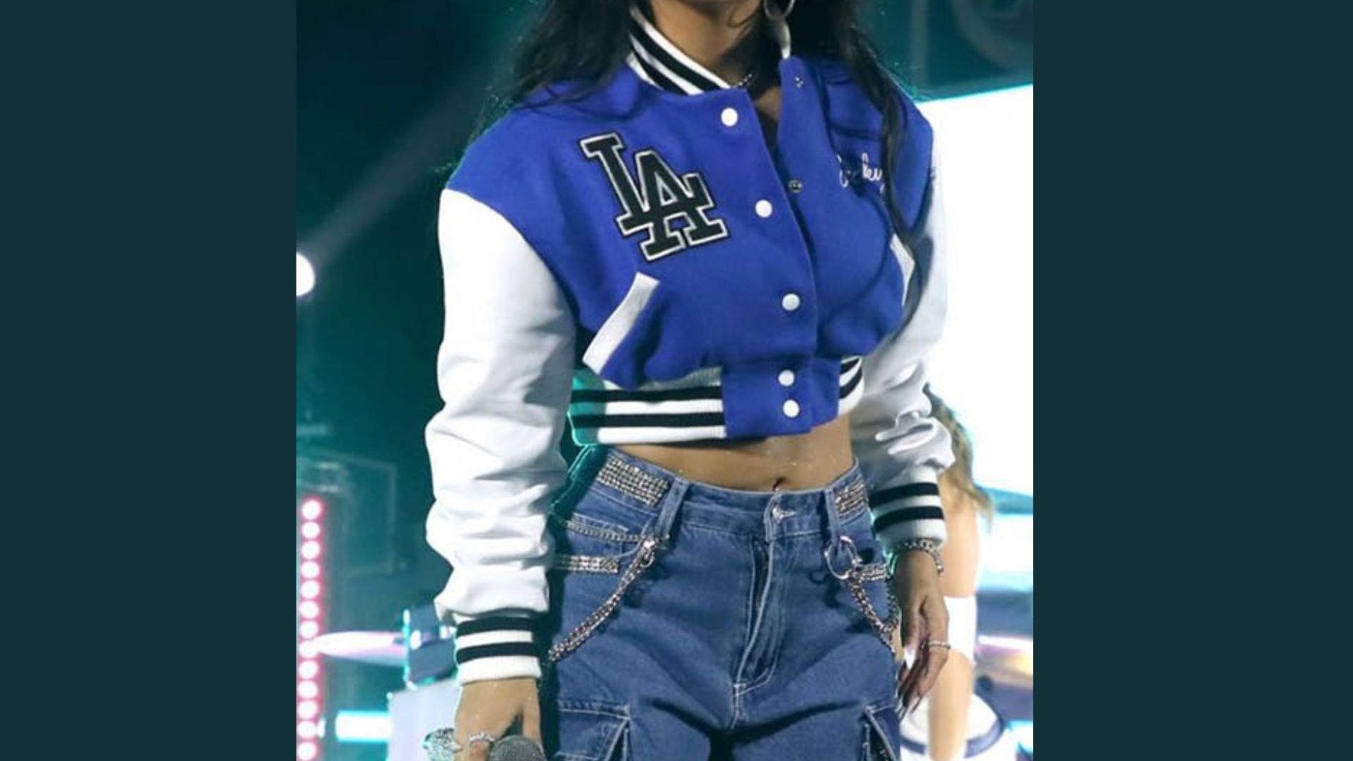 Rihanna wearing a blue and white Dodgers jacket, smiling and posing confidently for the camera.