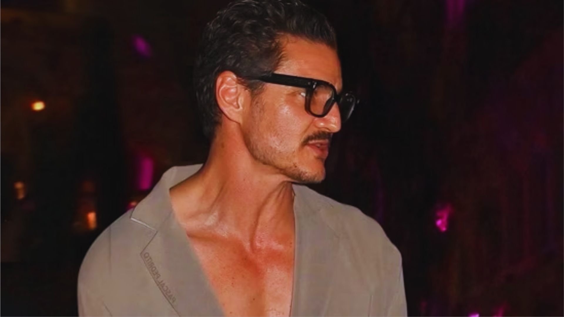 A man wearing glasses and a shirt stands confidently, looking directly at the camera.