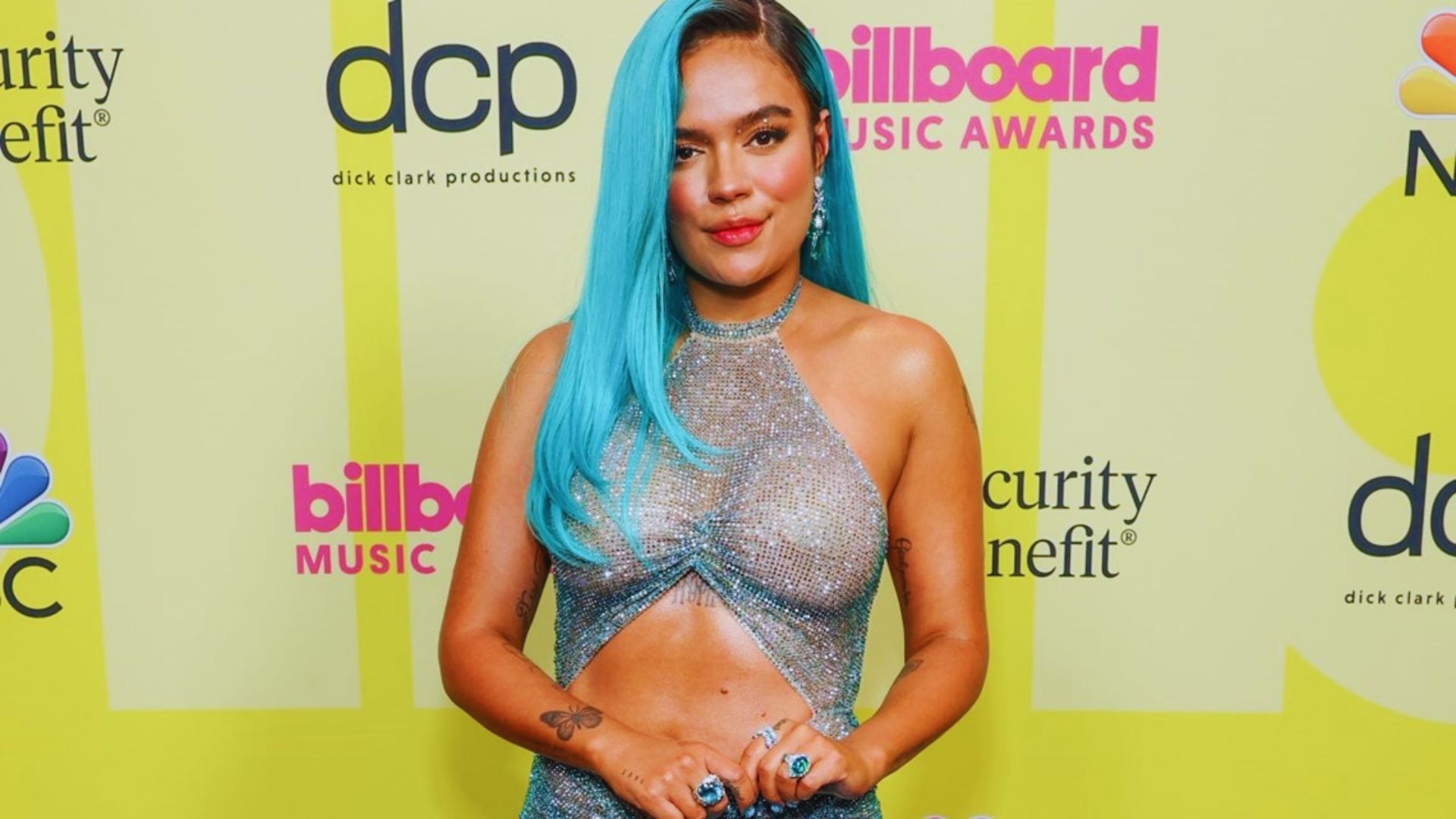 A woman with blue hair and a blue dress poses confidently at the Billboard Awards, showcasing her unique style.