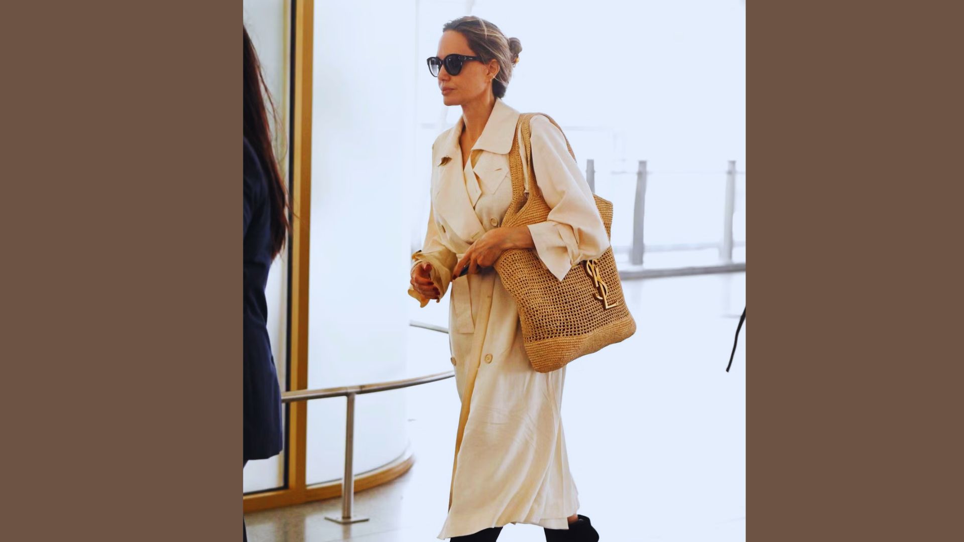 Angelina Jolie, wearing a white dress and sunglasses, walks gracefully through the airport, embodying a modern style.