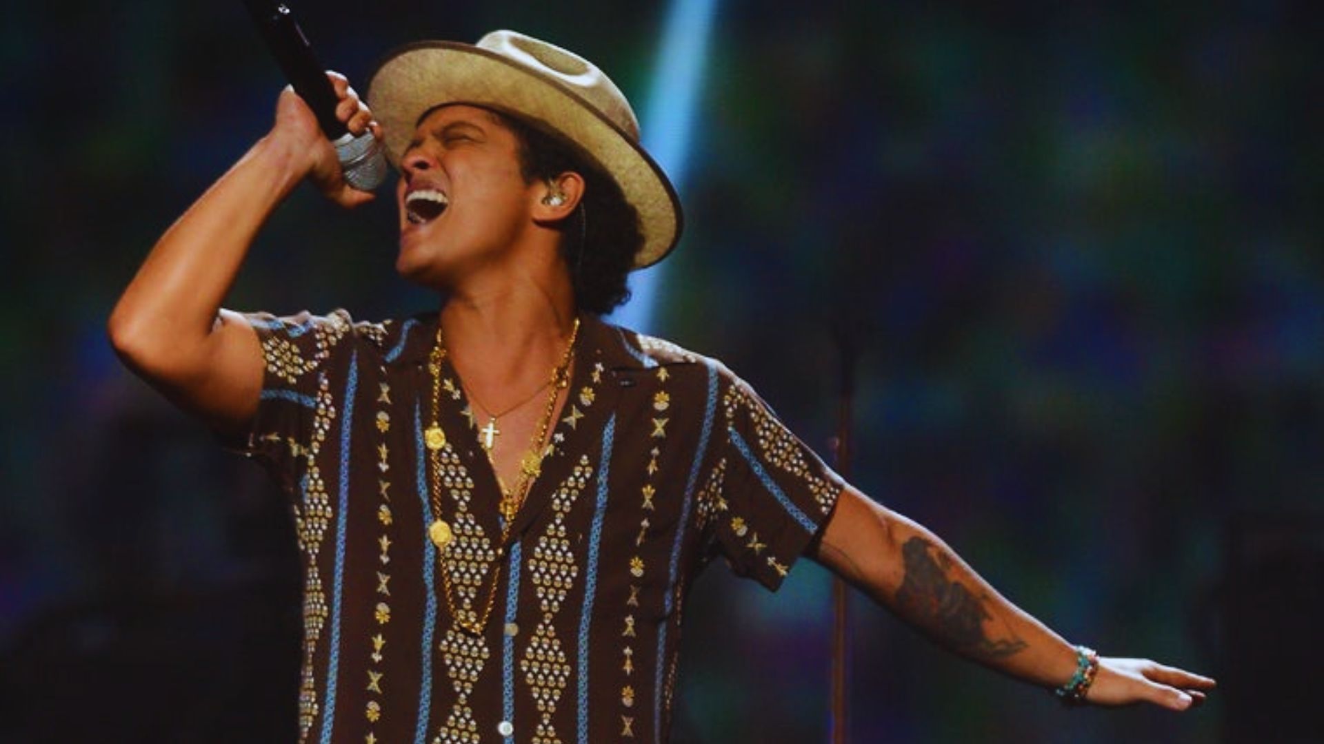 Bruno Mars in stylish shirt singing, probably in a concert.