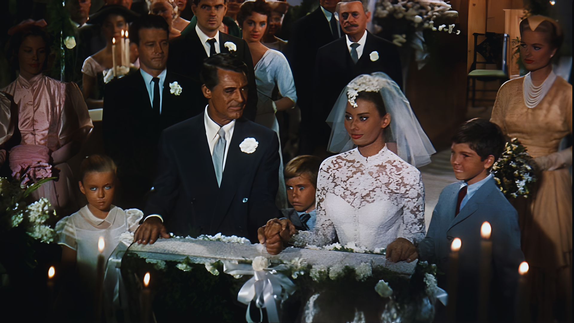 A bride and groom stand together, smiling in front of a beautifully decorated wedding cake.