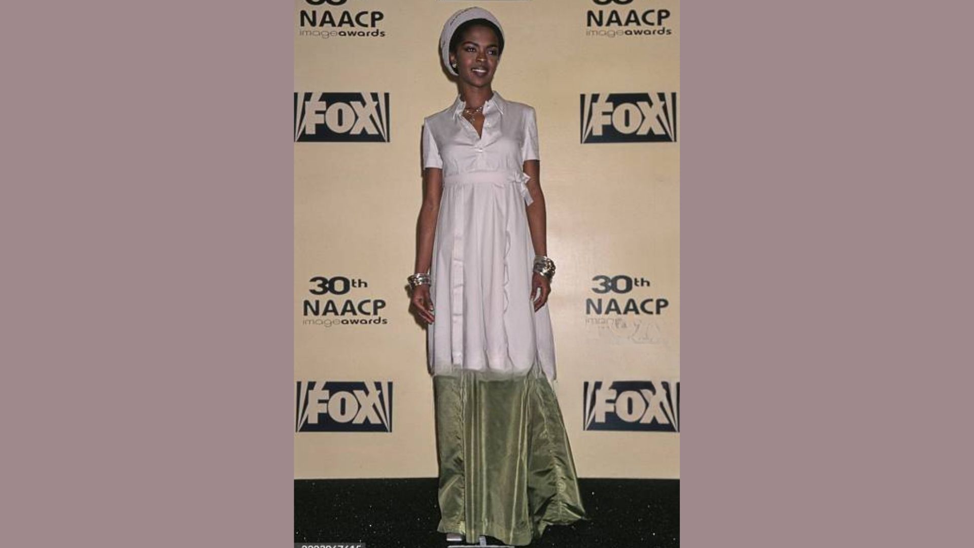 A person wearing a white dress and green hat attends the Fox Network's fall party, smiling amidst a festive atmosphere.