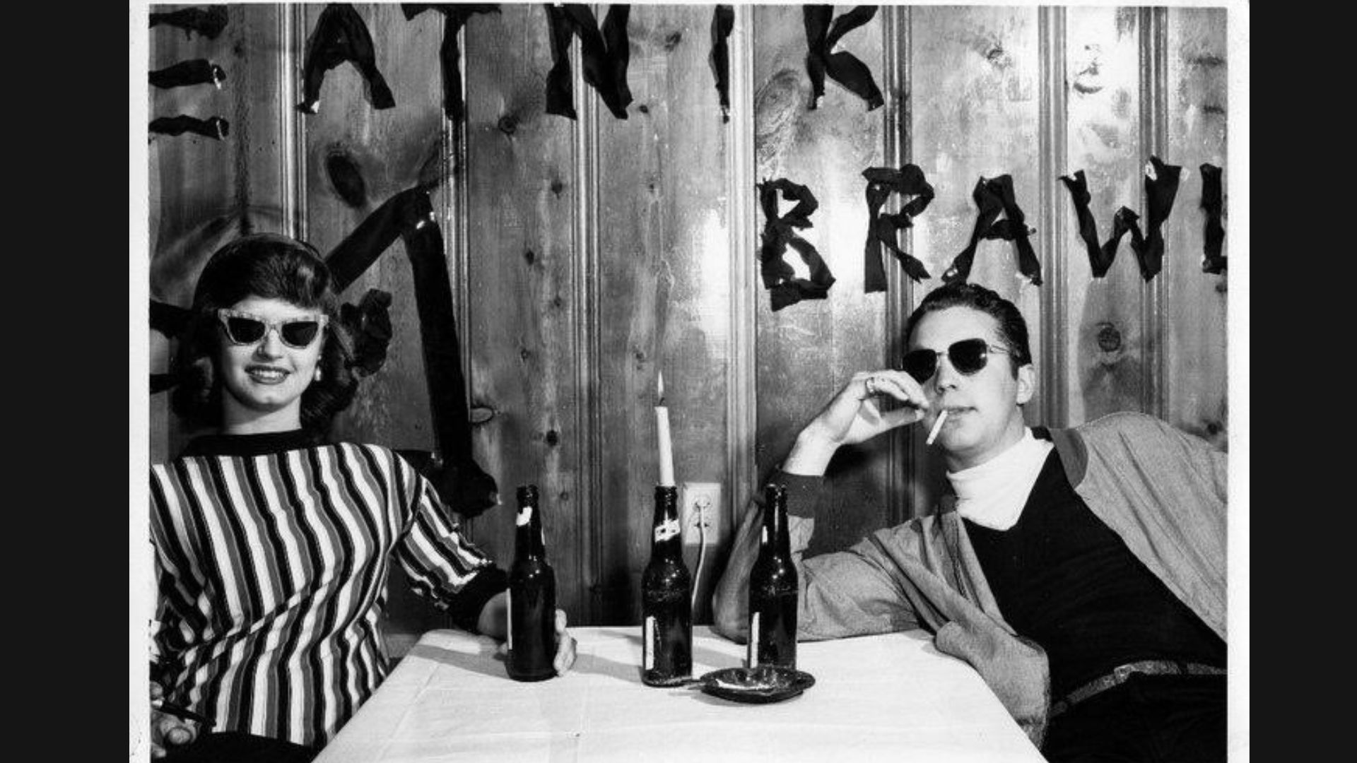 A man and woman sit at a table, enjoying drinks and engaged in conversation.
