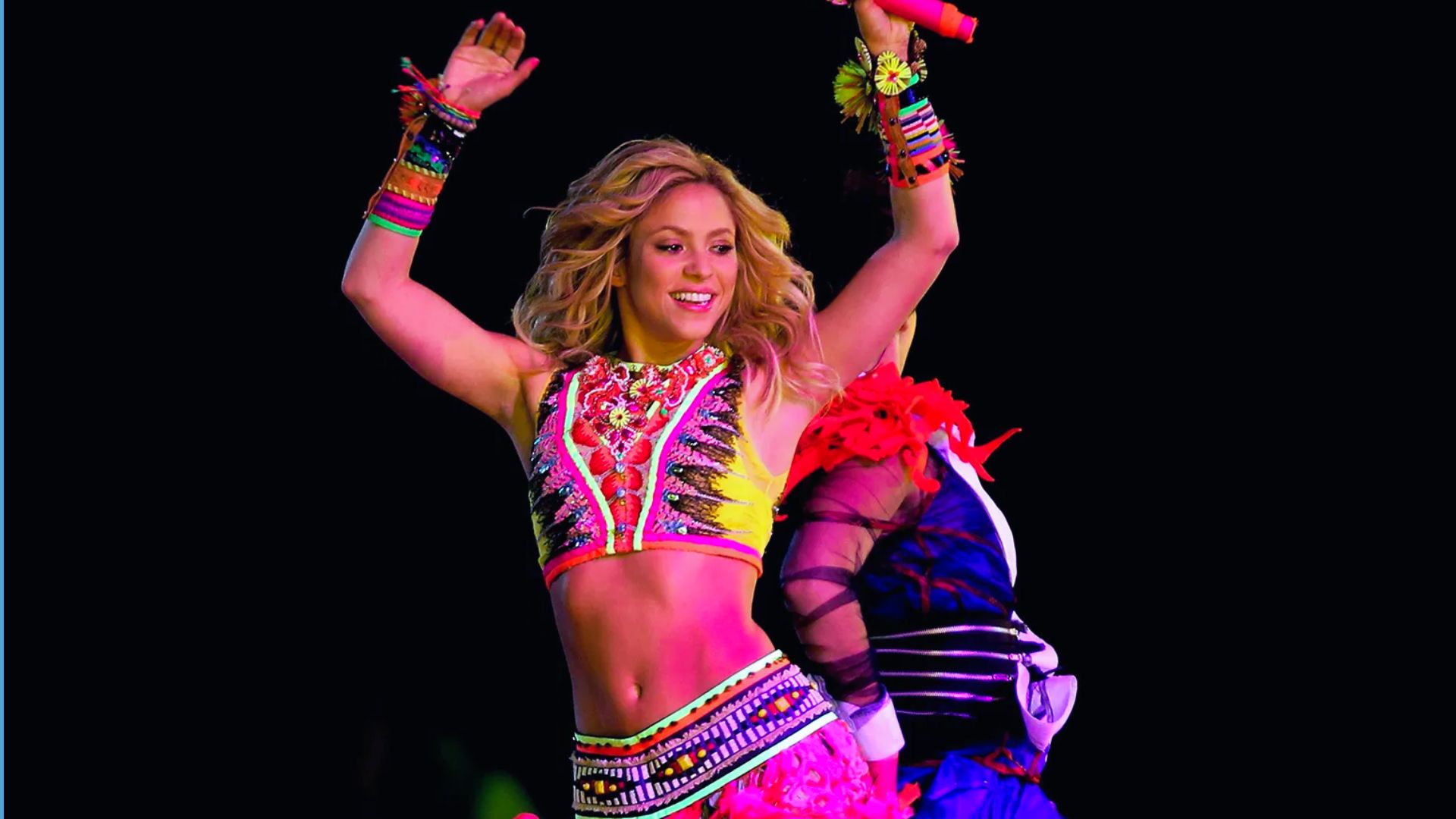 A woman in a vibrant outfit joyfully dances, showcasing her colorful attire and energetic movements.