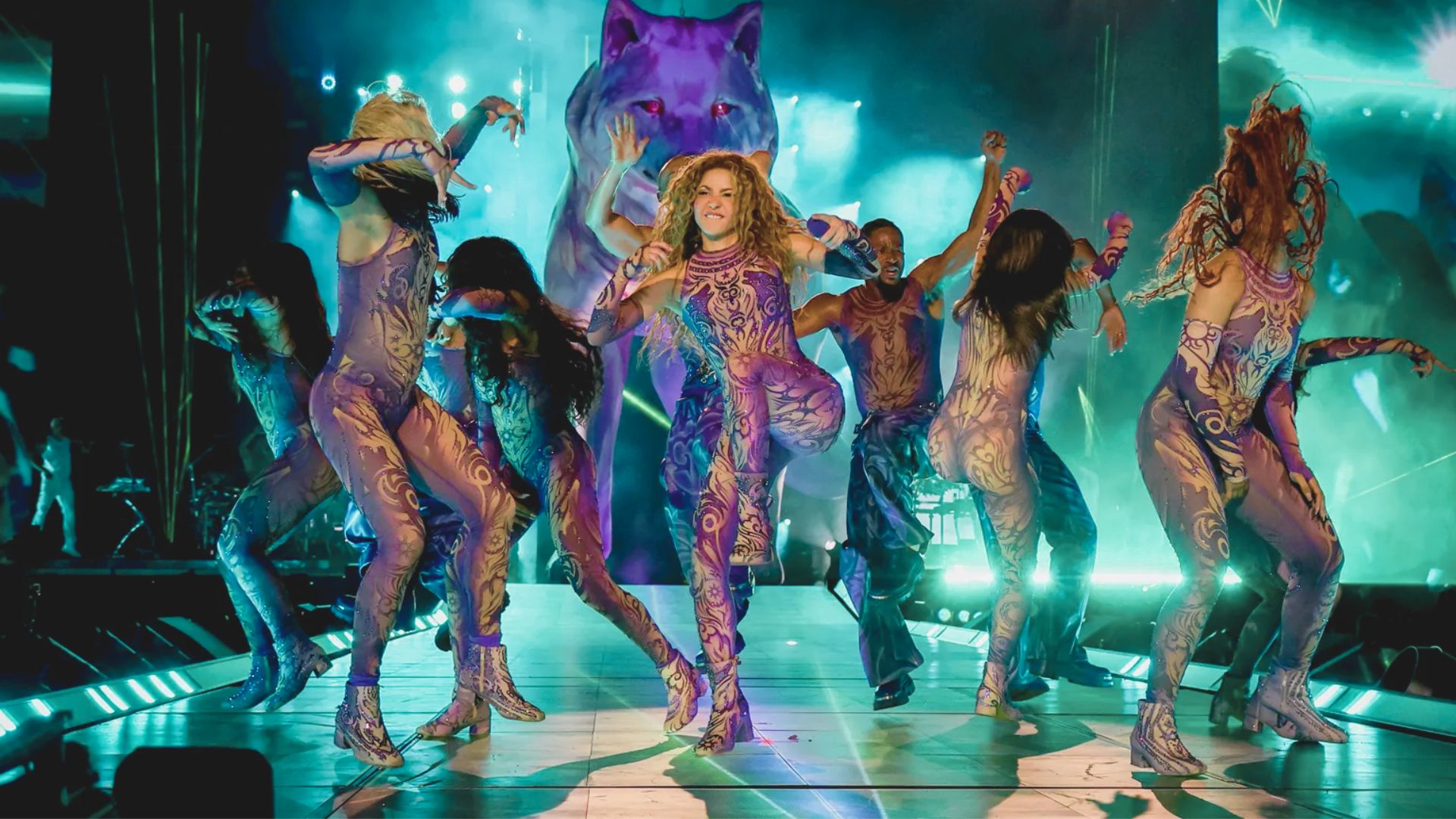 Jennifer Lopez performs on stage with her dancers, showcasing dynamic choreography and vibrant stage lighting.