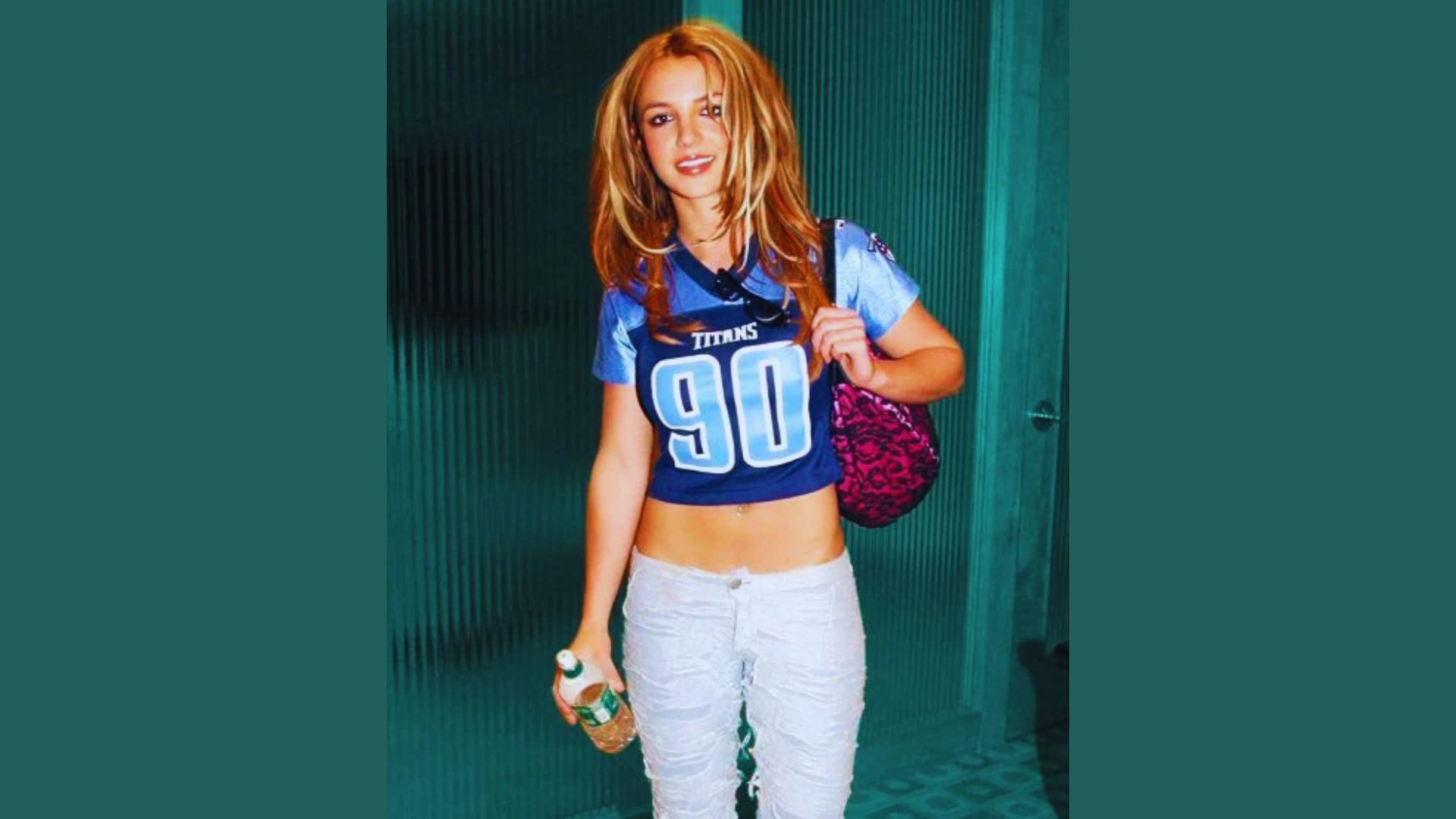 A young woman wearing a jersey and jeans stands confidently, showcasing a casual and sporty style.