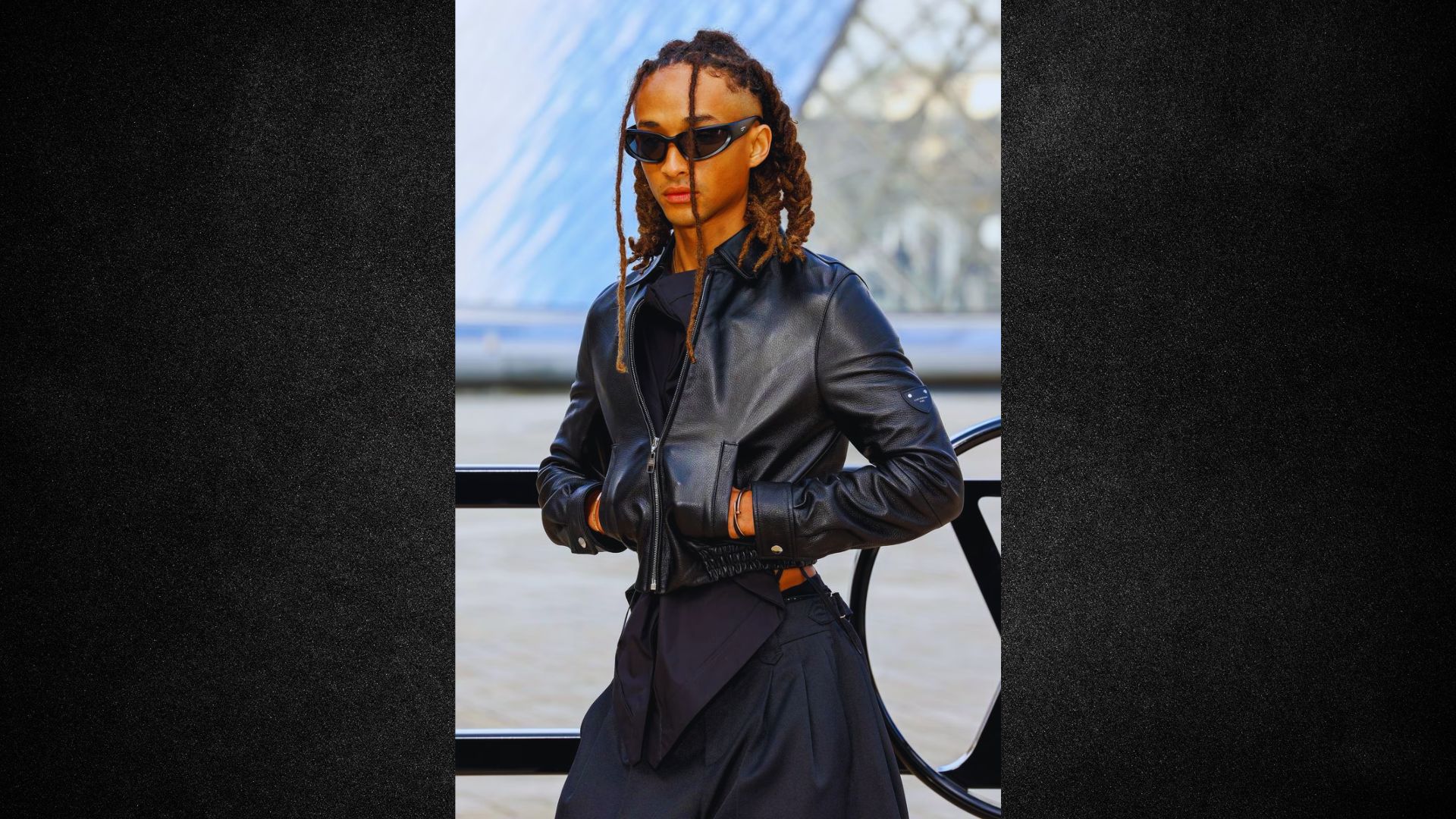 A woman with dreadlocks and sunglasses poses confidently, showcasing her unique style and personality.