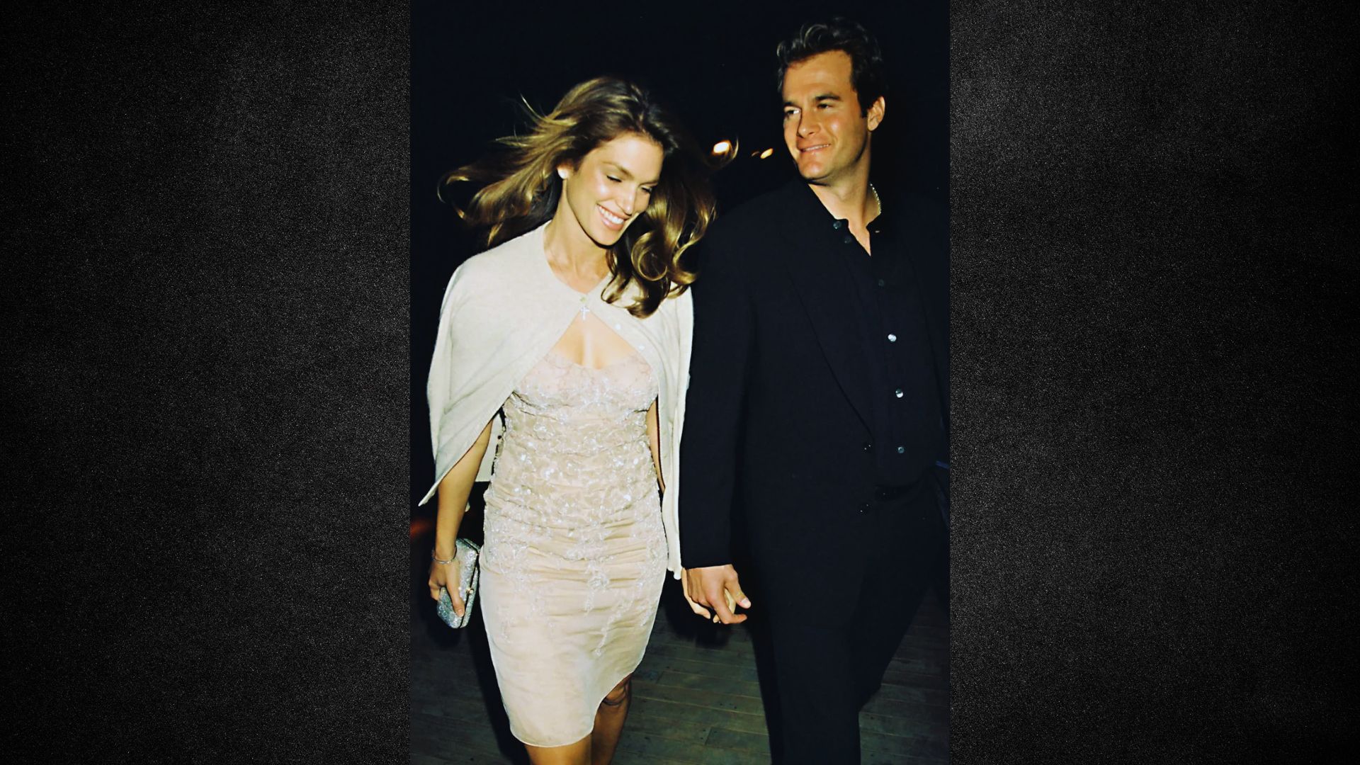 A man and woman in formal attire walking side by side, engaged in conversation.