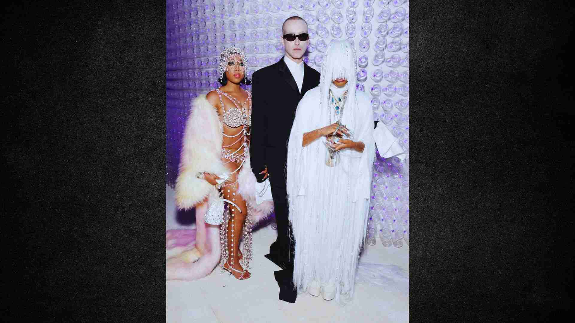 A man and woman dressed in white outfits pose together, standing closely with friendly expressions.