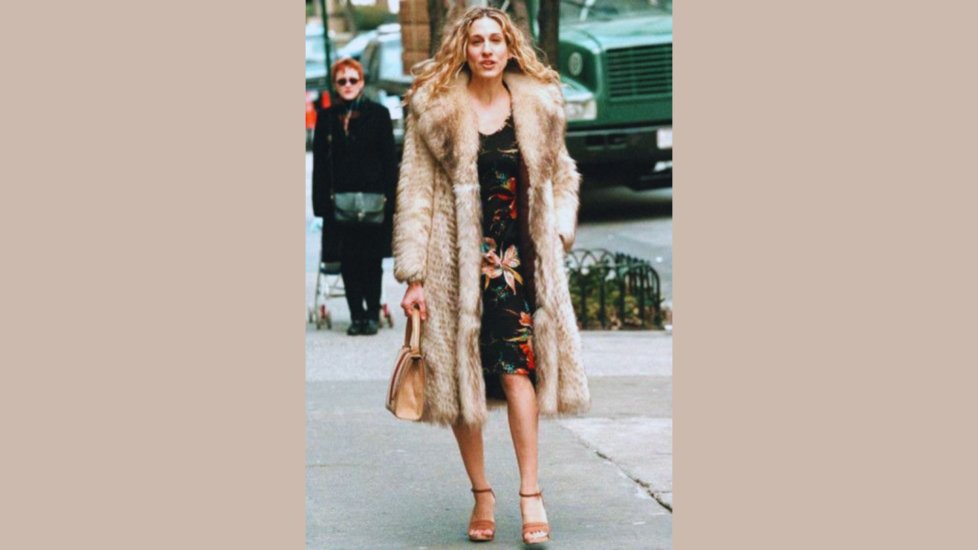 A woman in a fur coat and floral dress strolls down the street, showcasing a blend of elegance and style.