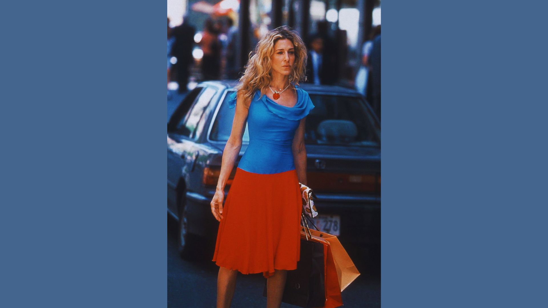 A woman wearing a blue top and a red skirt stands confidently, showcasing her vibrant outfit.