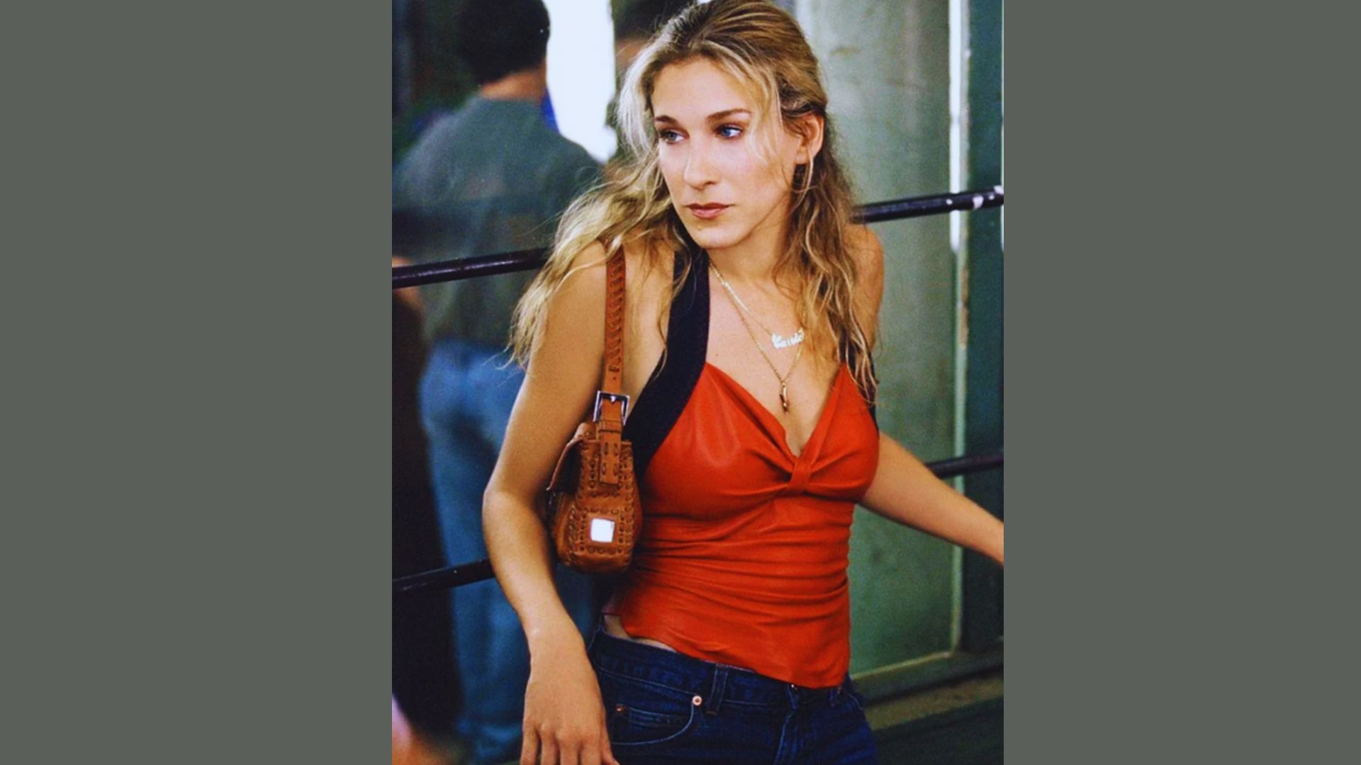 A woman wearing jeans and a red top stands confidently, showcasing a casual yet stylish outfit.