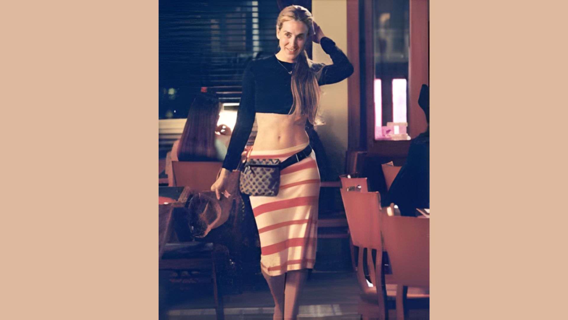 A woman in a skirt and top walks through a restaurant, showcasing a casual dining atmosphere.