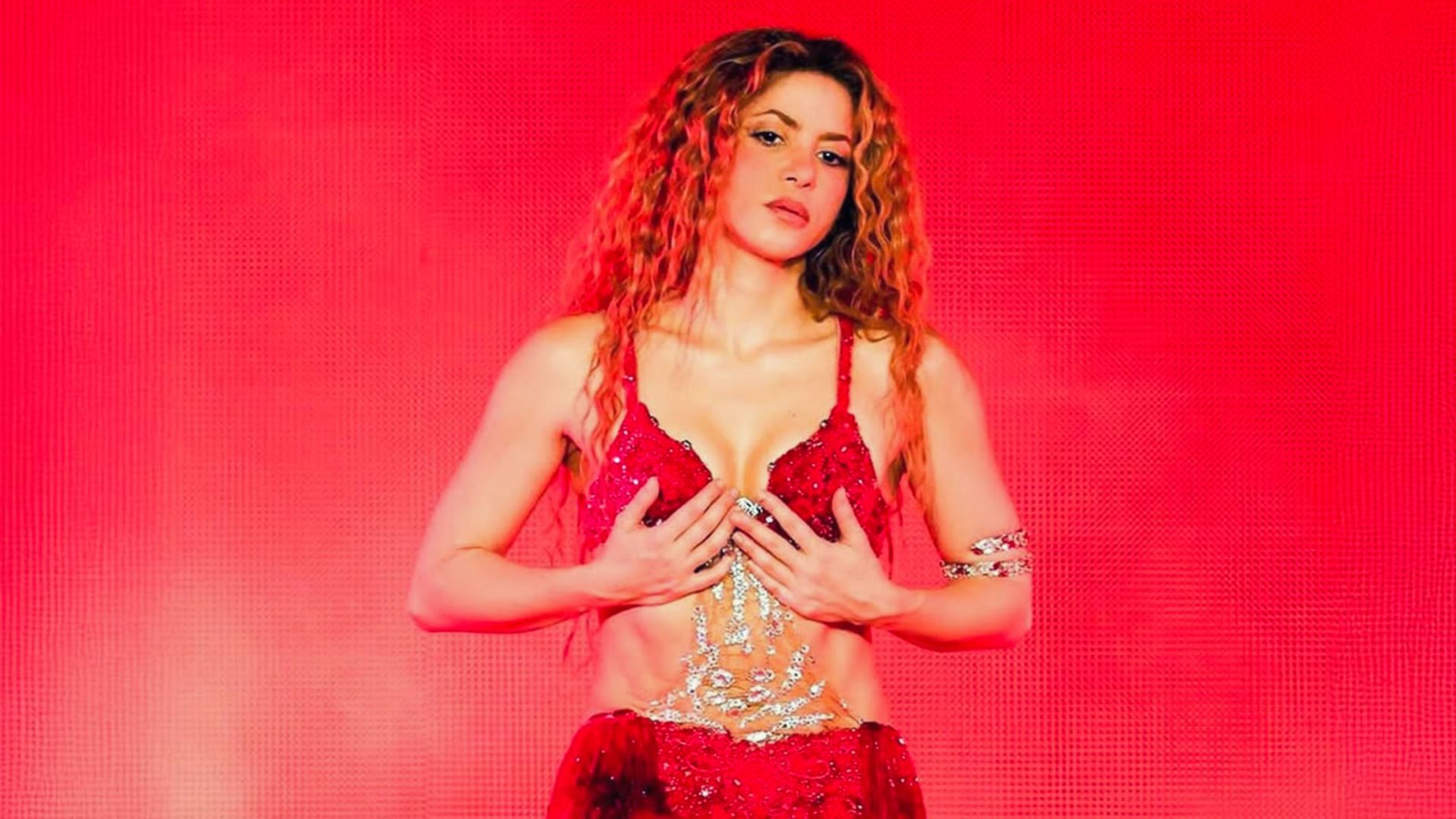 A woman in a red bikini confidently poses on stage, showcasing her figure and the vibrant color of her outfit.
