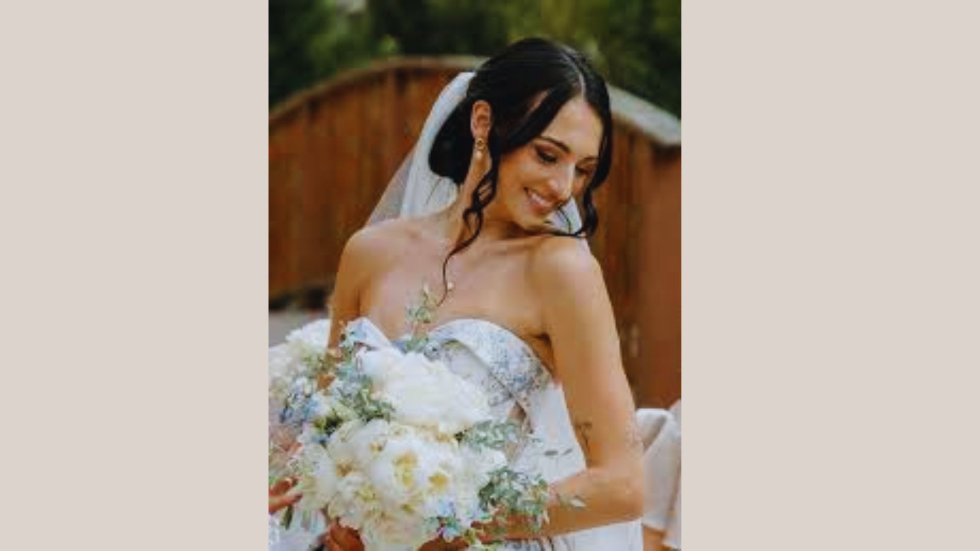 A woman in a wedding dress holds a bouquet, smiling joyfully on her special day.