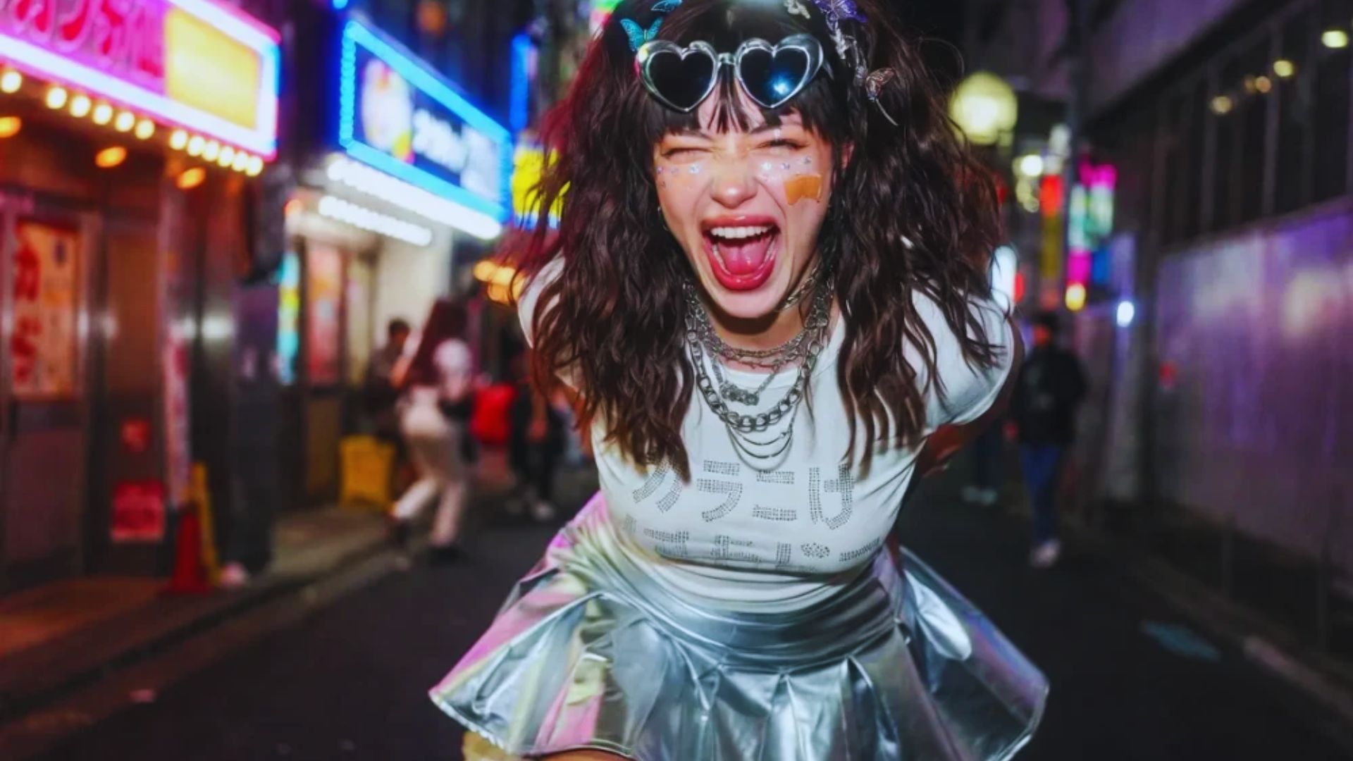 A woman wearing a silver skirt and glasses poses for a photo, smiling confidently at the camera.