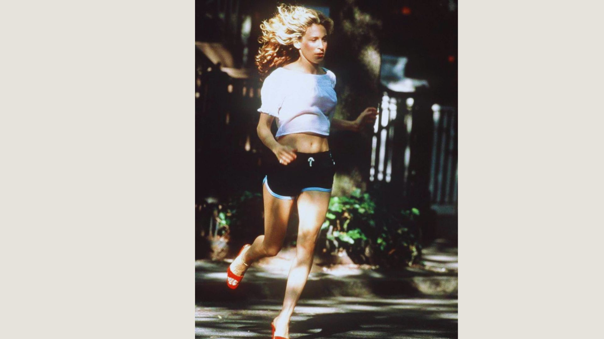 A woman wearing shorts and a white shirt is running outdoors, showcasing an active lifestyle.