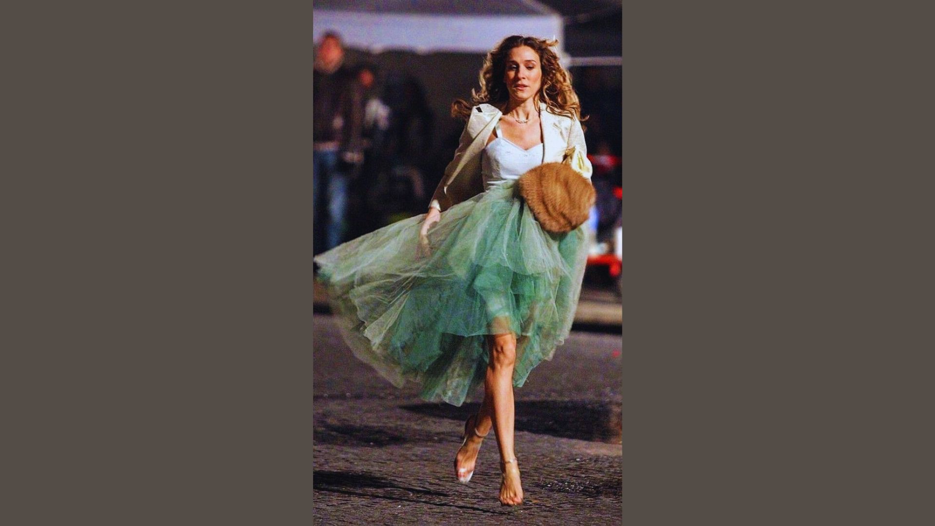 A woman in a green skirt walks down the street, surrounded by urban scenery.