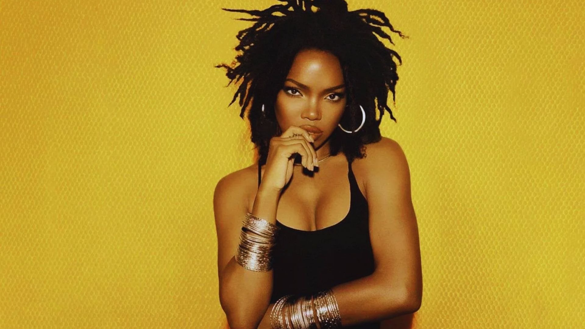 A woman with dreadlocks smiles and poses for a photo, showcasing her unique hairstyle and confident demeanor.