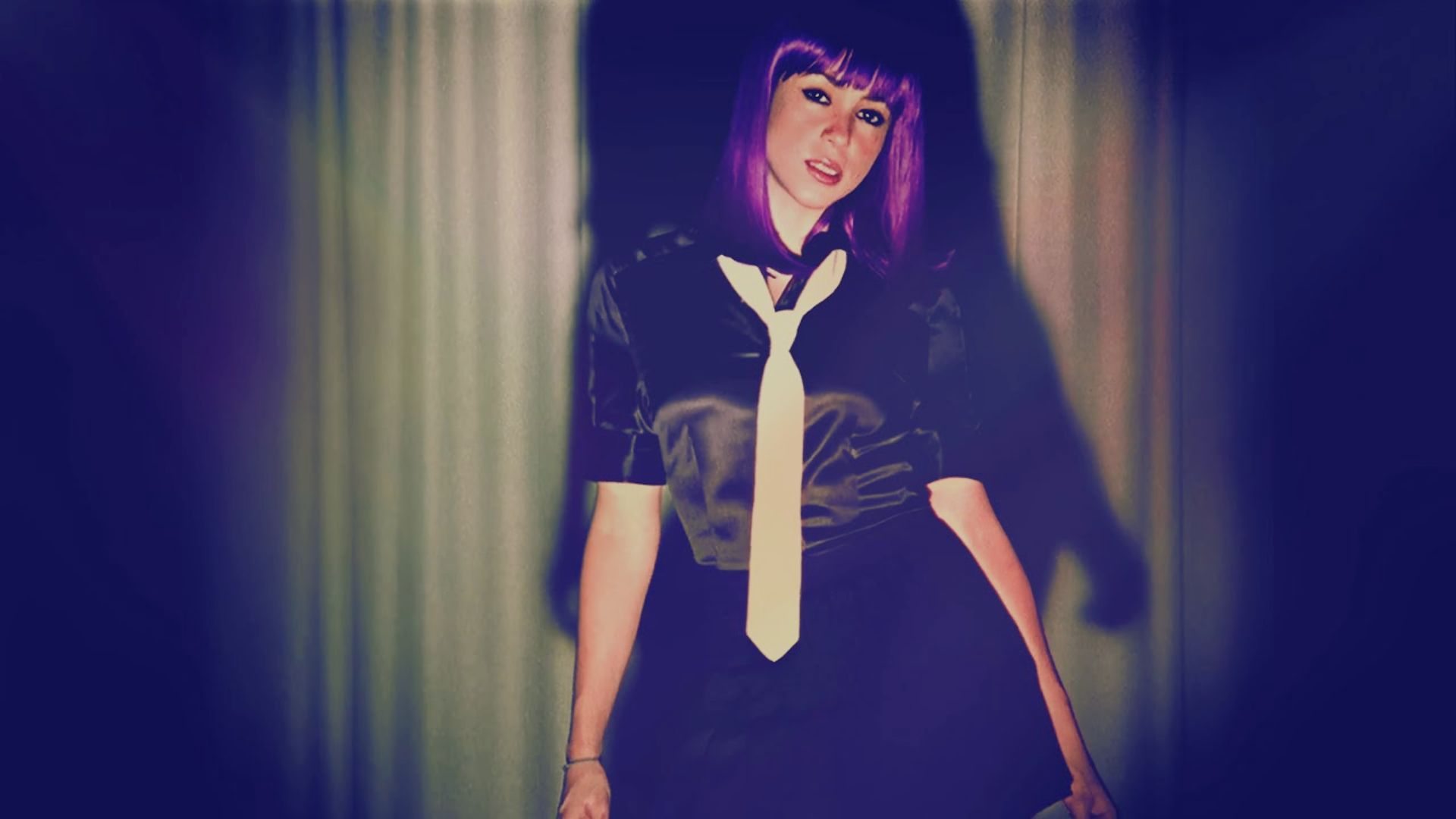 A woman with vibrant purple hair wearing a stylish tie, showcasing a unique and bold fashion choice.