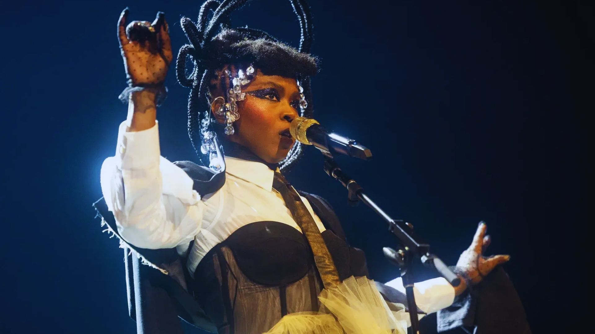A woman with dreadlocks holds a microphone, ready to speak or perform, exuding confidence and engagement.