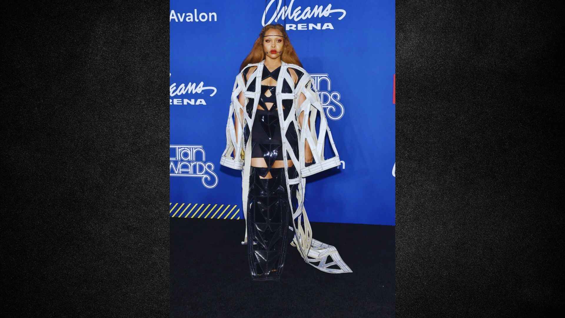 The singer is performing in a stylish black and white dress, showcasing a blend of elegance and modern fashion.