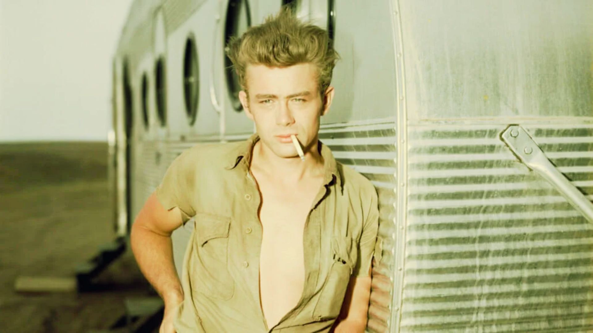 James Dean poses in the desert, showcasing his iconic hairstyle and classic 1950s fashion style.