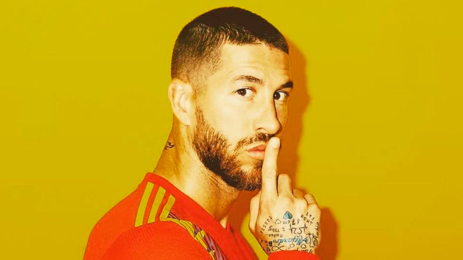 Sergio Ramos with tattoos gestures for silence by placing his finger to his lips, relating to trending haircuts.