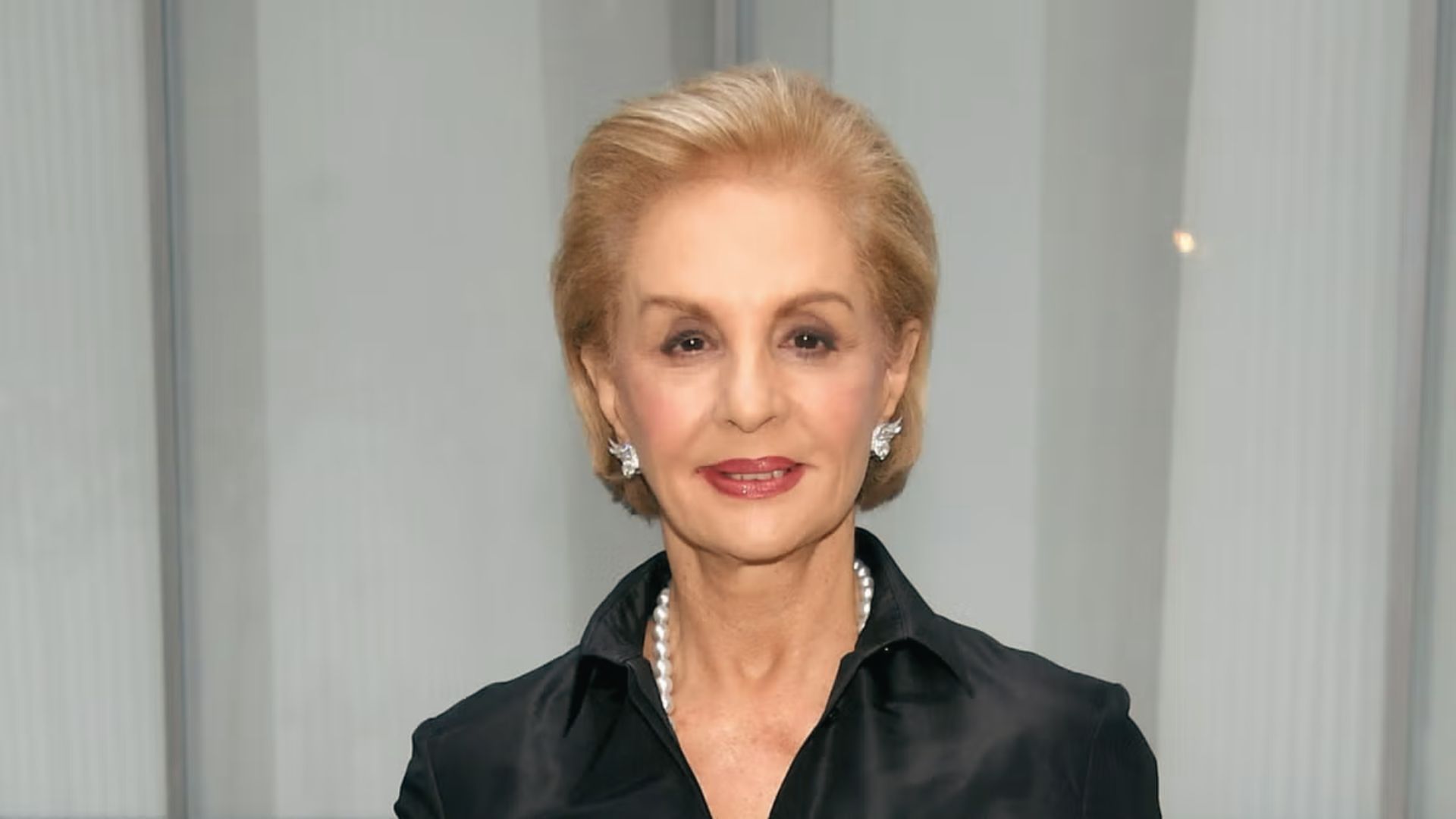 Portrait of fashion designer Carolina Herrera wearing a black satin shirt.