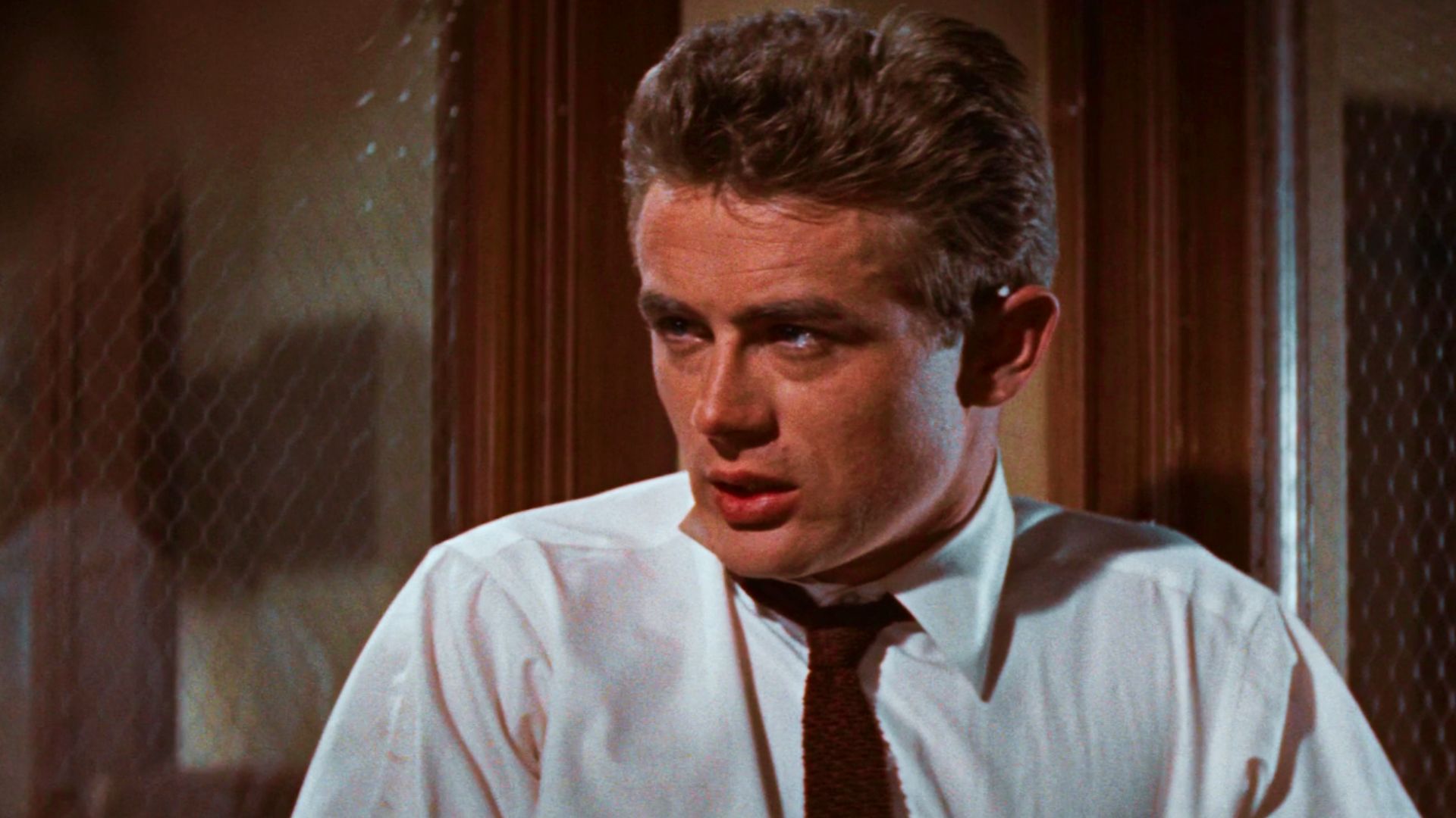 James Dean in a white shirt and tie gazes thoughtfully, referencing a guide on haircut for face shapes.