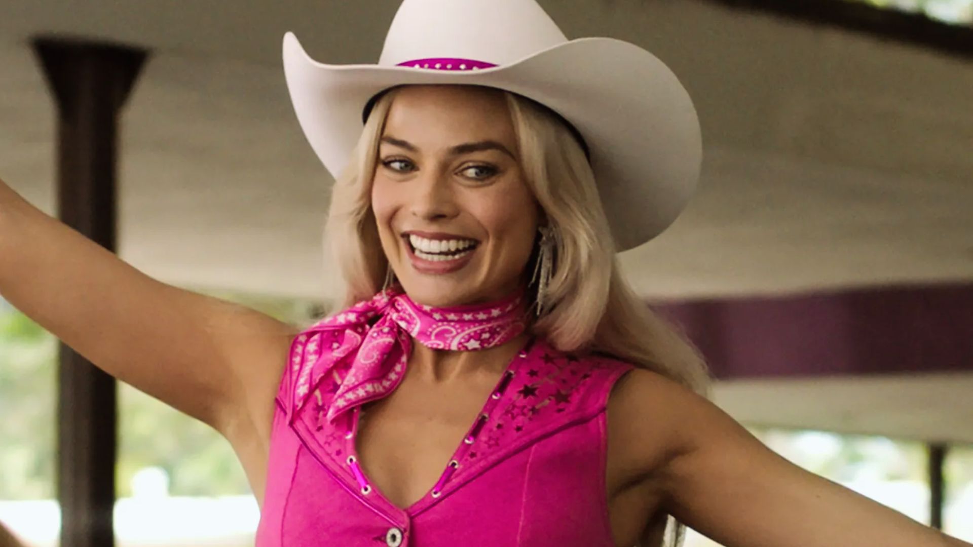"A woman wearing a pink dress and a cowboy hat stands confidently, blending elegance with rustic charm."