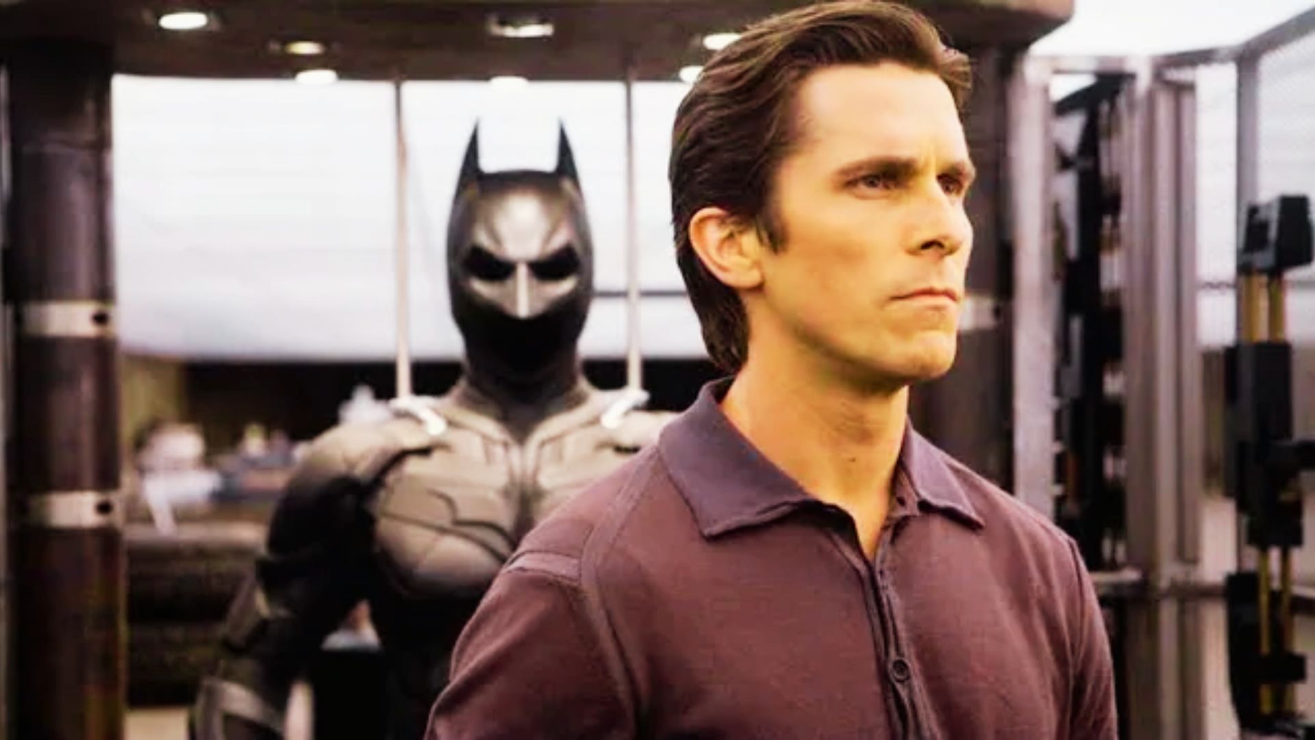 Batman in a dark, brooding pose from "The Dark Knight Rises," showcasing Christian Bale's iconic hairstyle.