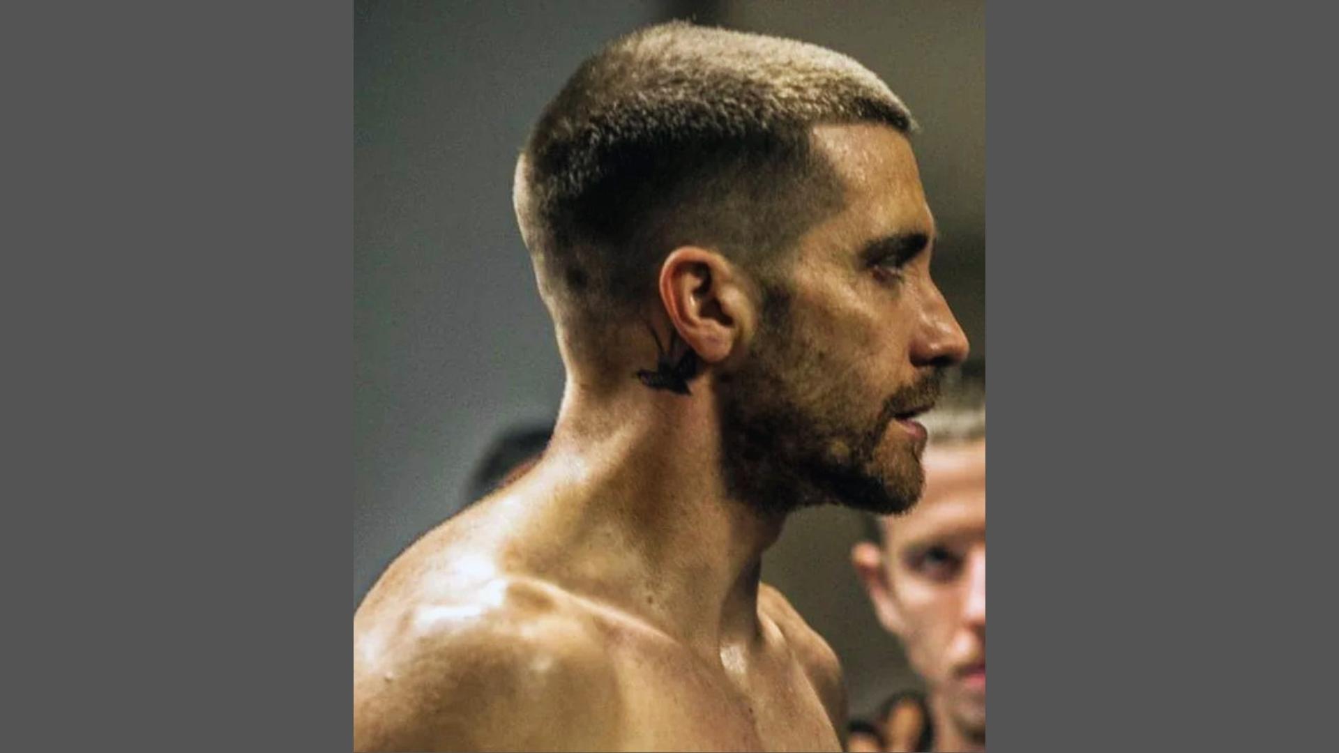 Jake Gyllenhaal in Southpaw with close-cropped buzz cut haircut, neck tattoo, and stubble in side profile.